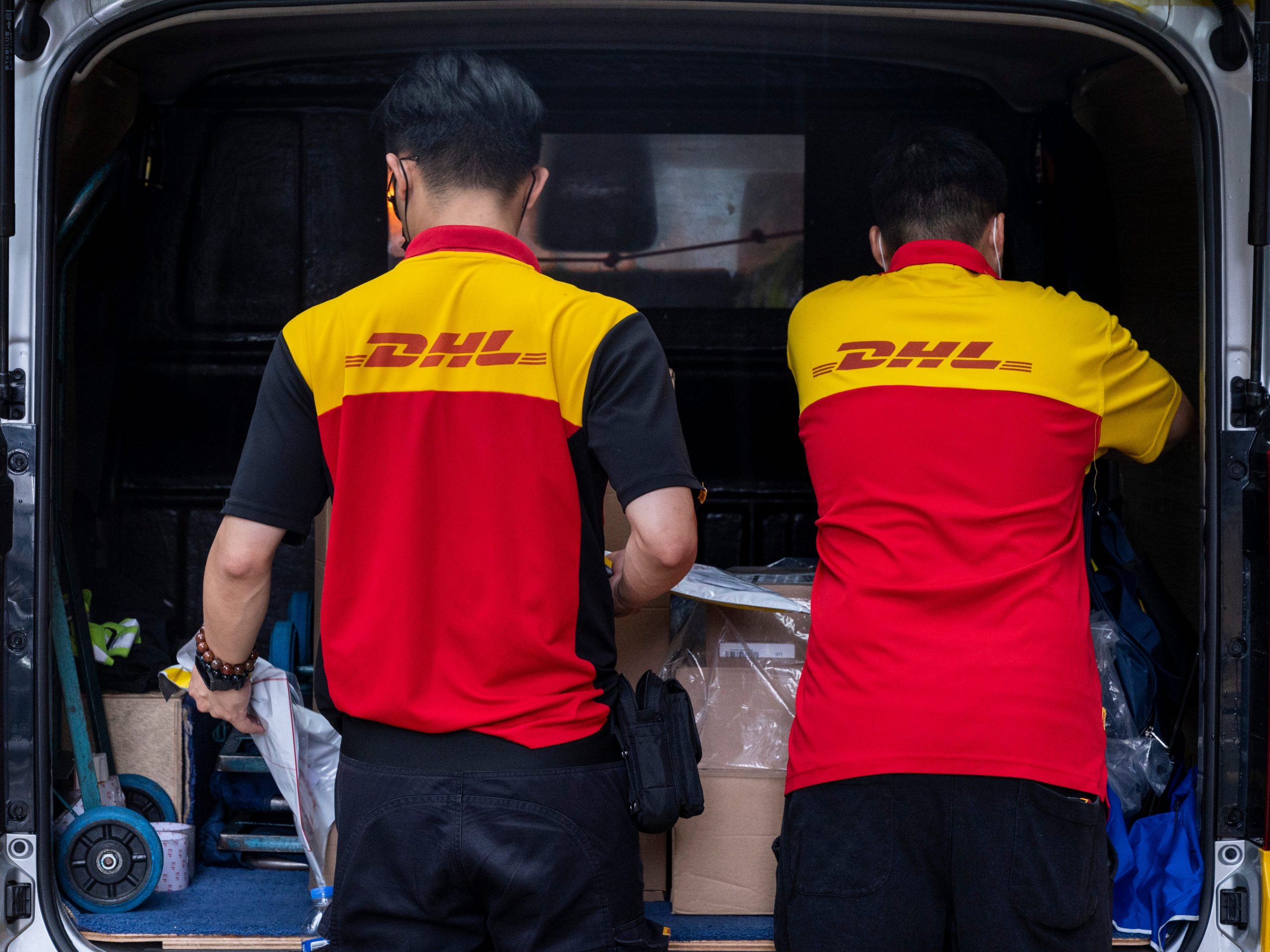 DHL delivery drivers at the back of a van