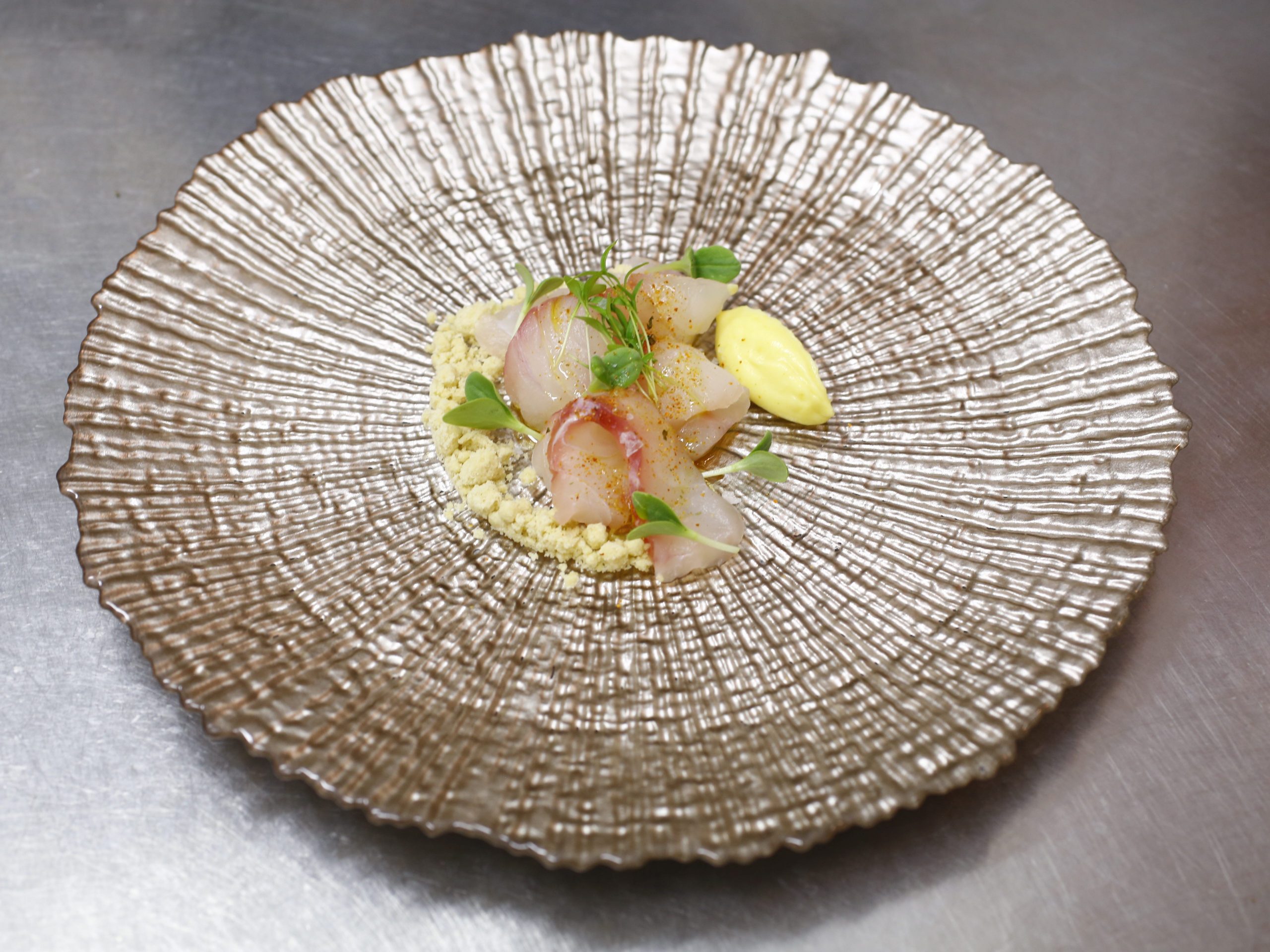 A seafood dish on large plate resembling a seashell.