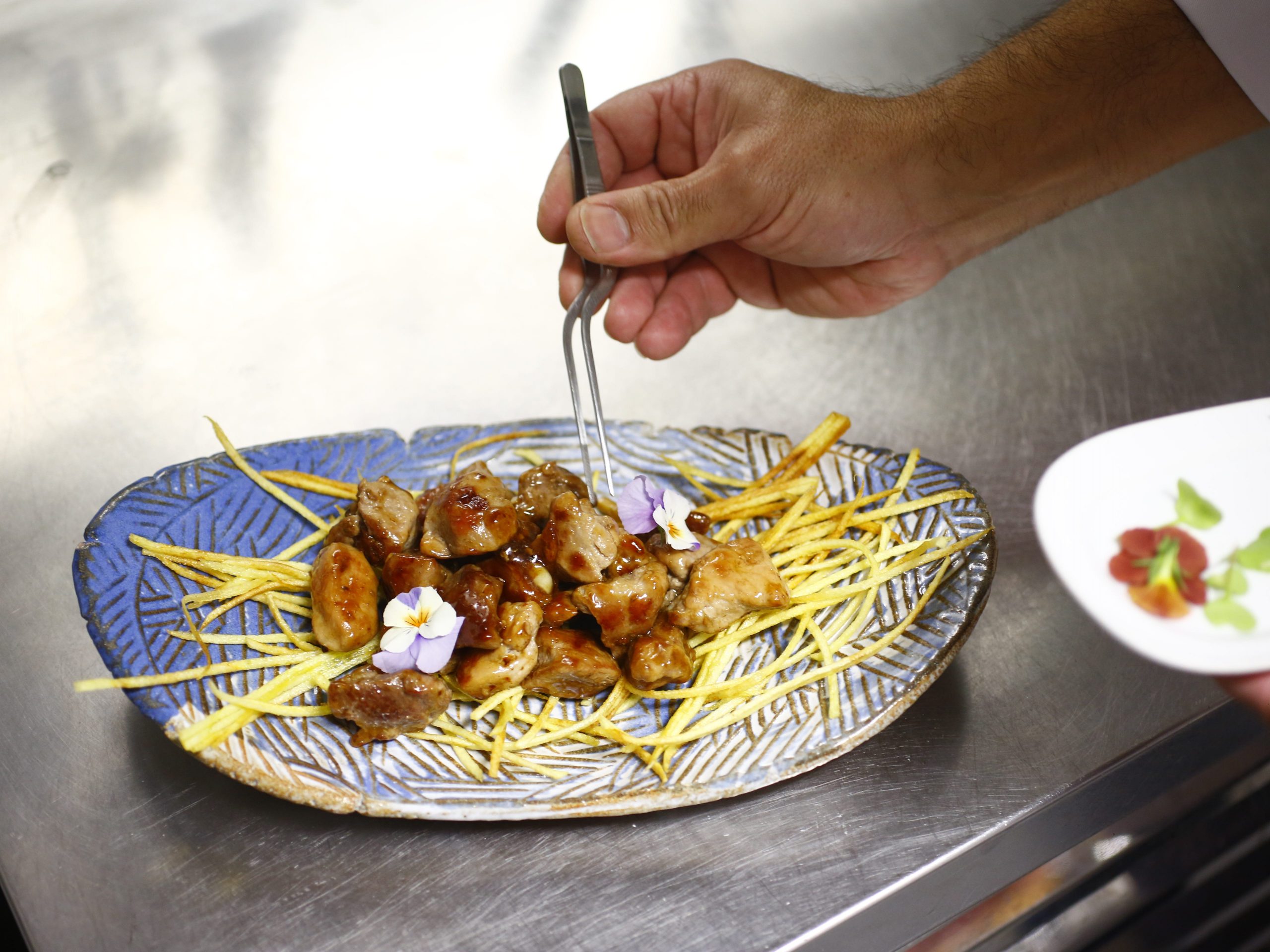 A hand holding a fork to pick up the meat in a Canarian dish.