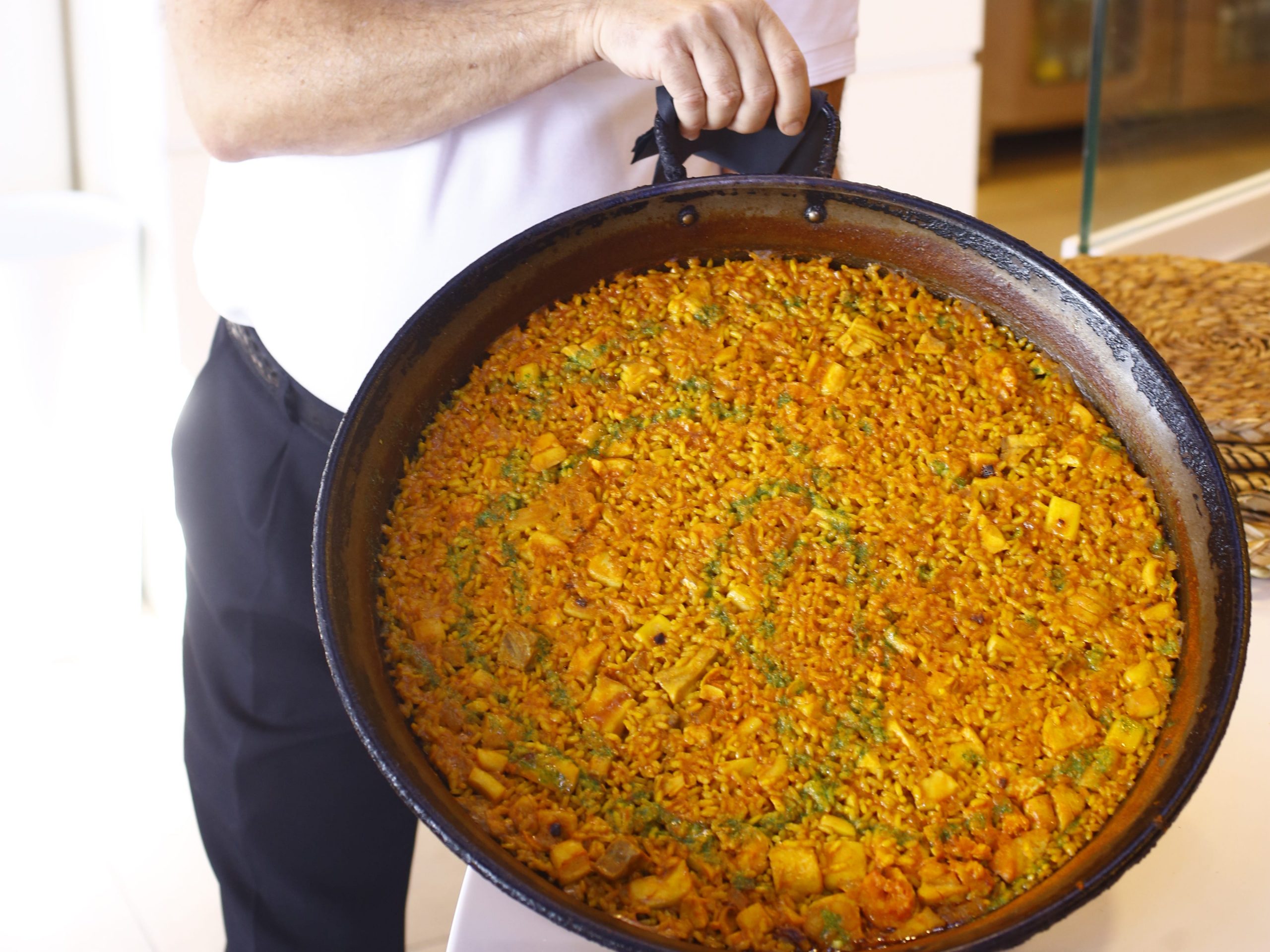 A man holding a large pan of paella