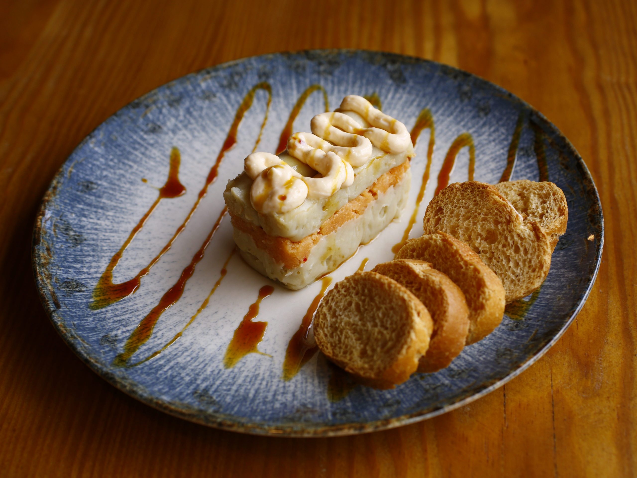 A dessert cake alongside several pieces of shortbread on a plate drizzled with sauce.