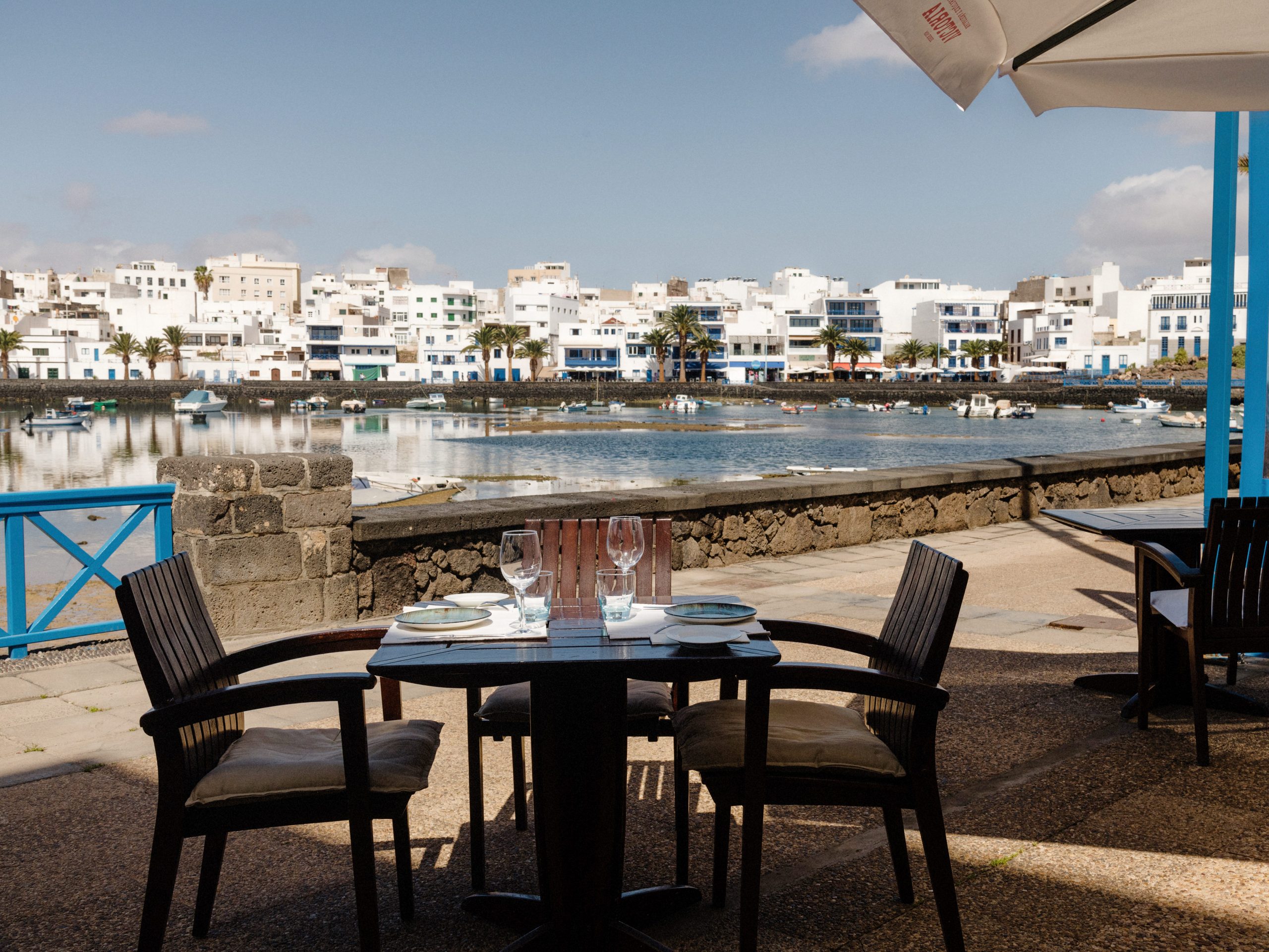 A small table and two chairs on a deck alongside the water.