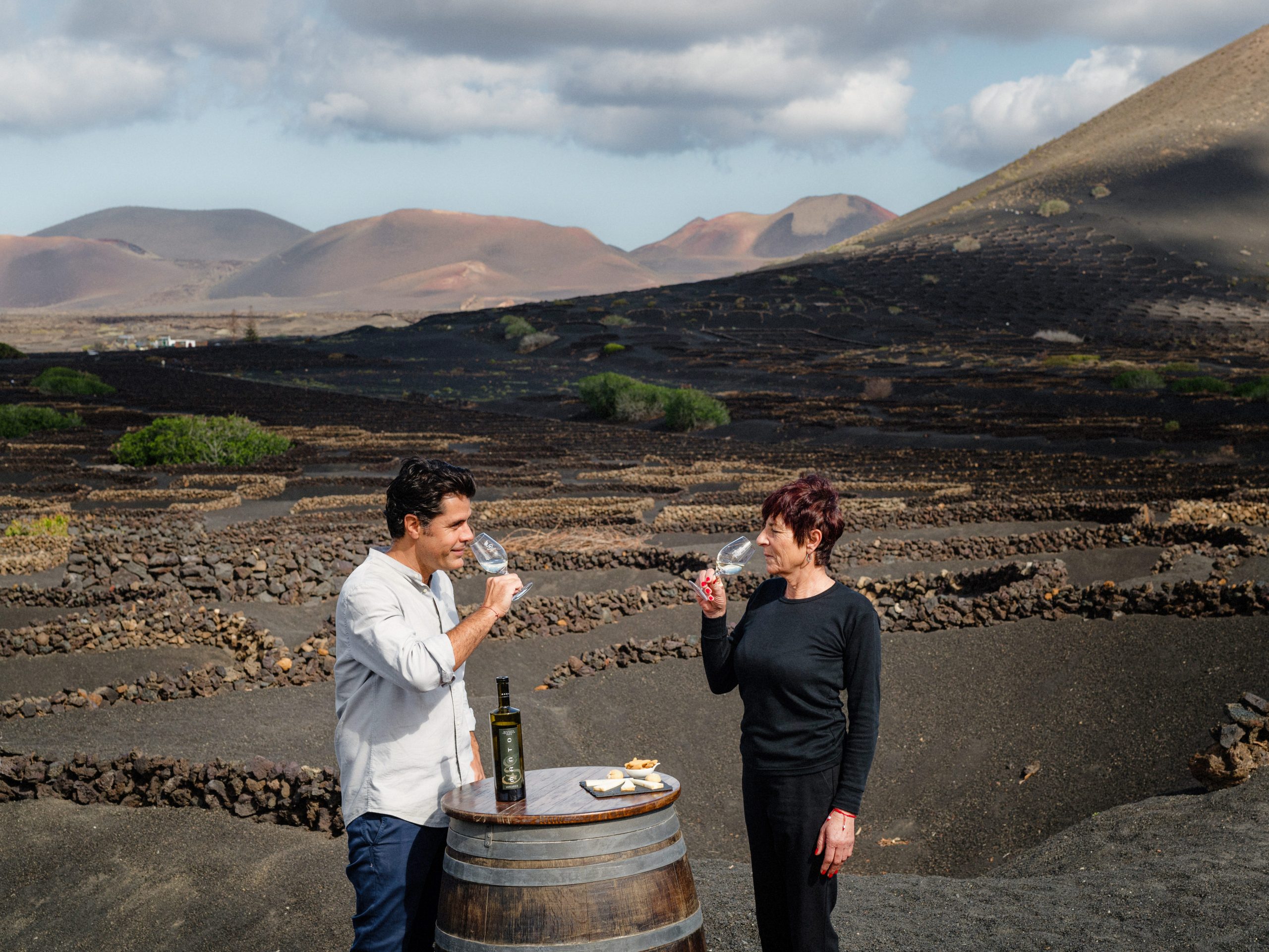 Two people sampling wine in a lava field on Lanzarote, Canary Islands