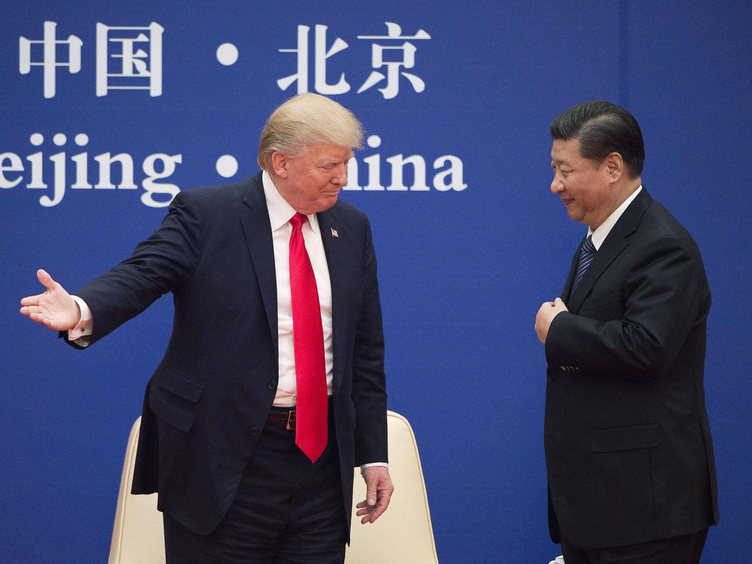 US President Donald Trump (L) gestures next to China's President Xi Jinping during a business leaders event at the Great Hall of the People in Beijing on November 9, 2017.