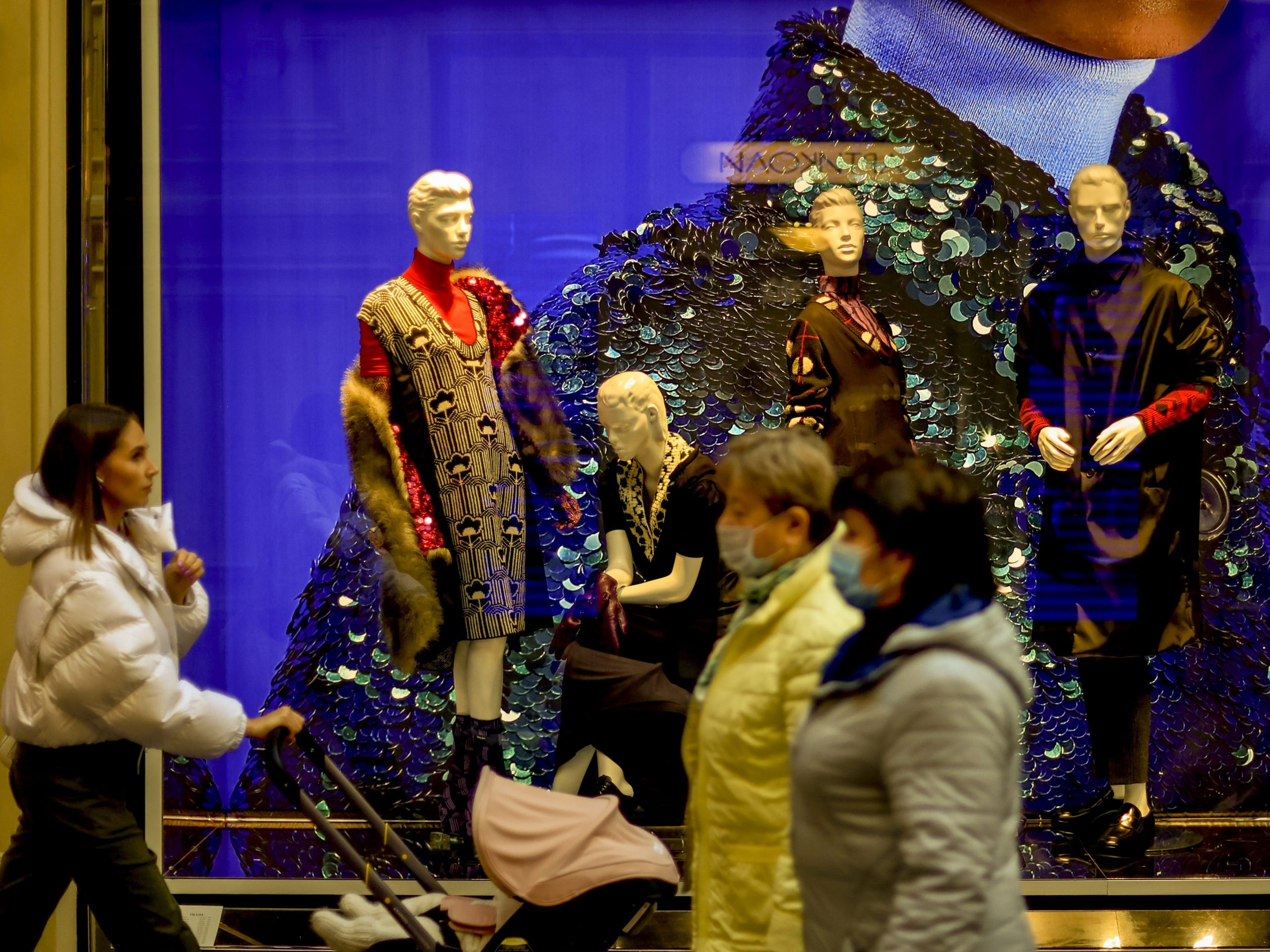 People walking past a Prada window at luxury mall GUM in Moscow, Russia.