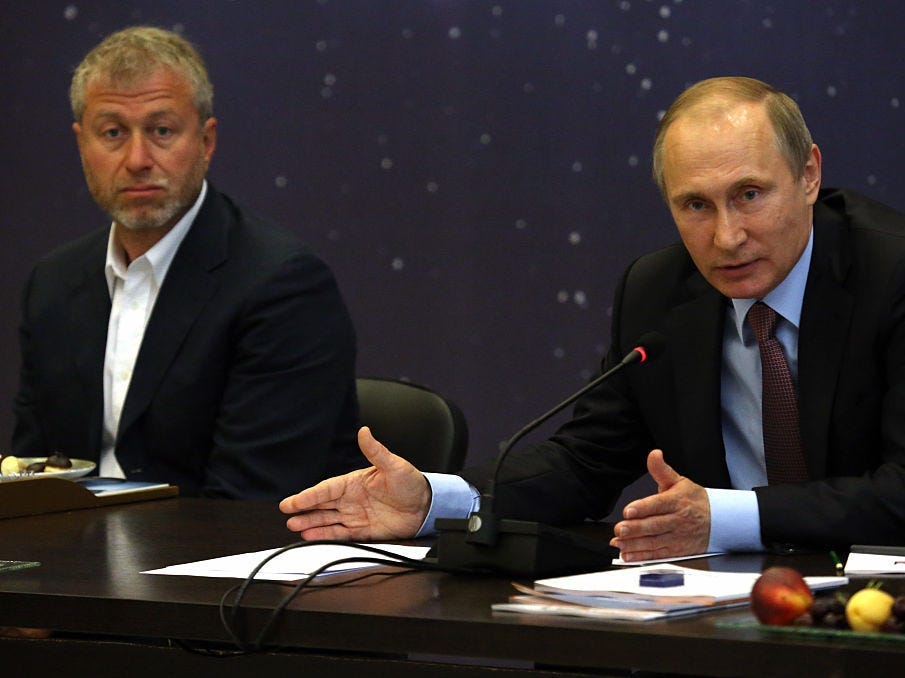 Russian President Vladimir Putin (R) speaks as billionaire and businessman Roman Abramovich (L) looks on during a meeting with top businessmen