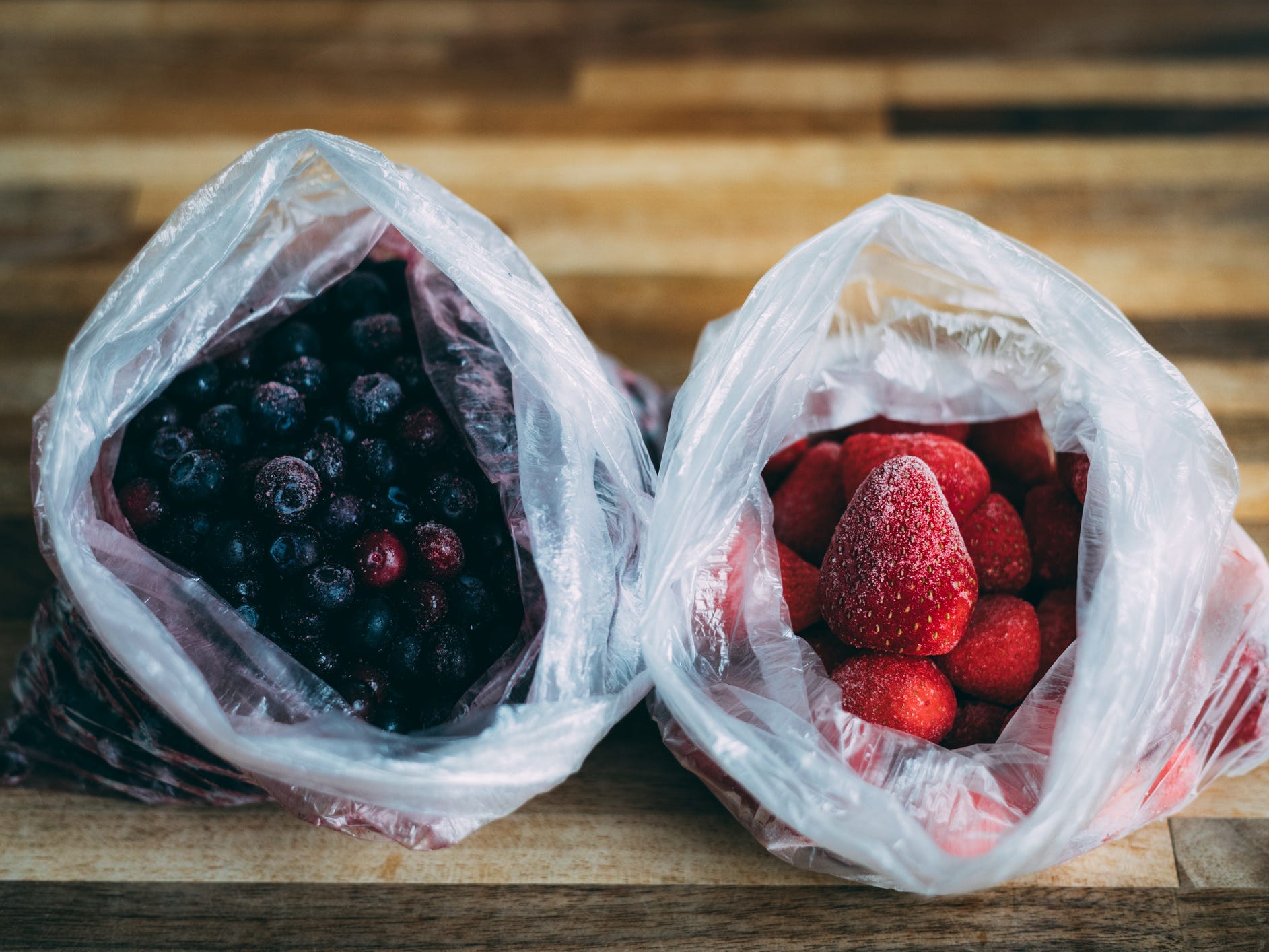 Frozen strawberries and frozen blueberries in their own plastic bags