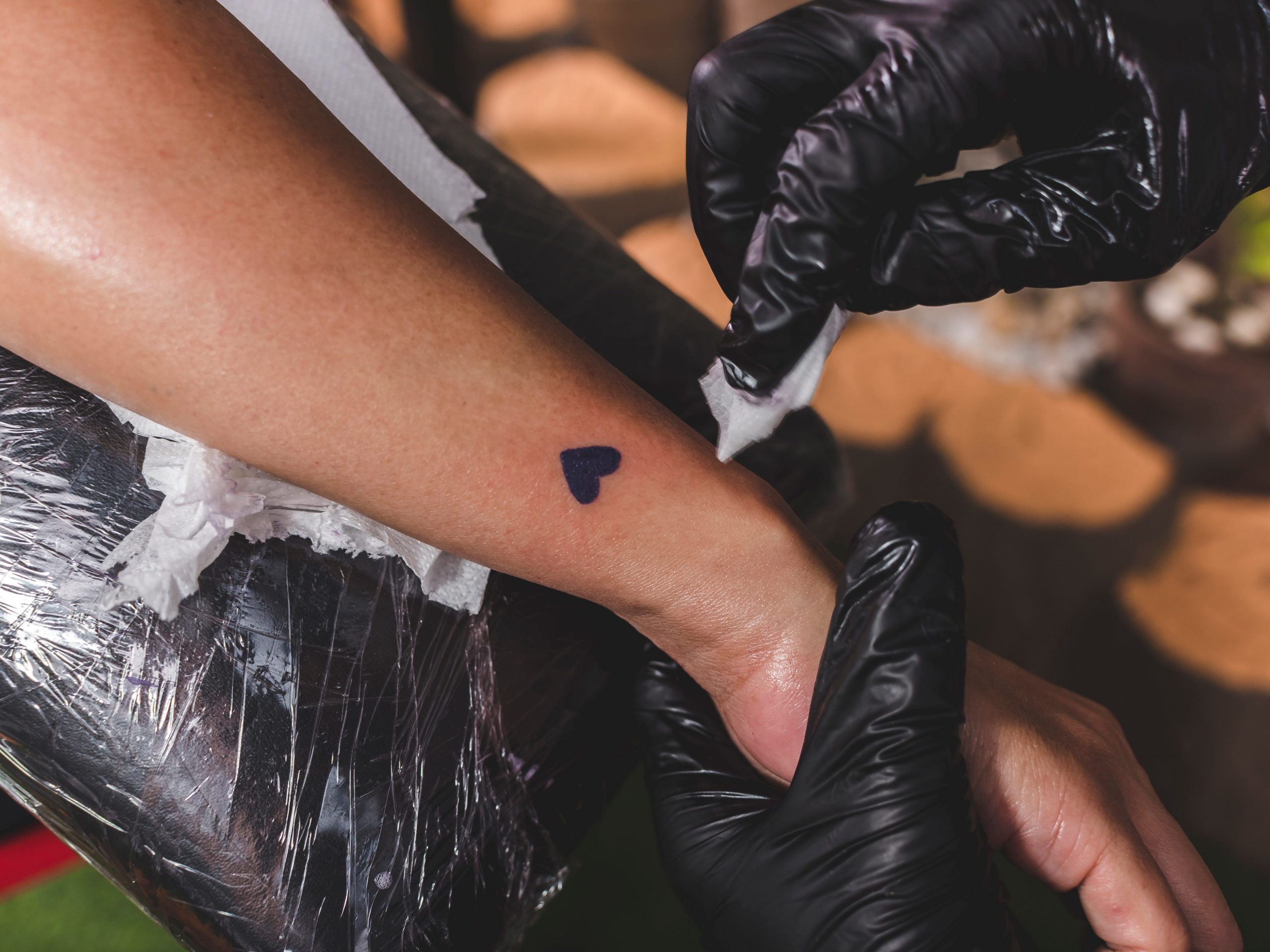 Person with completed tiny heart tattoo near wrist