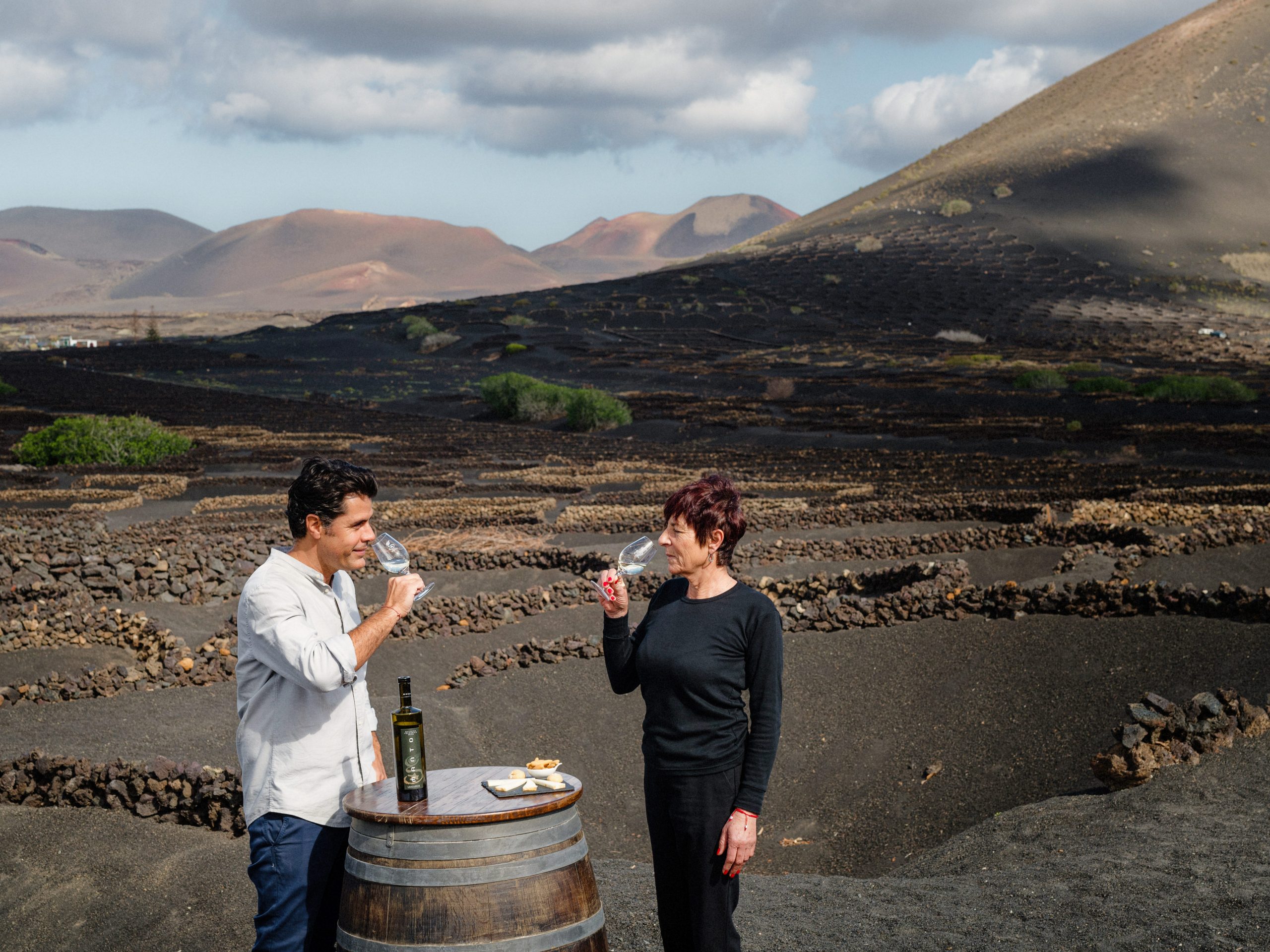 Two people sampling wine in a lava field on Lanzarote, Canary Islands