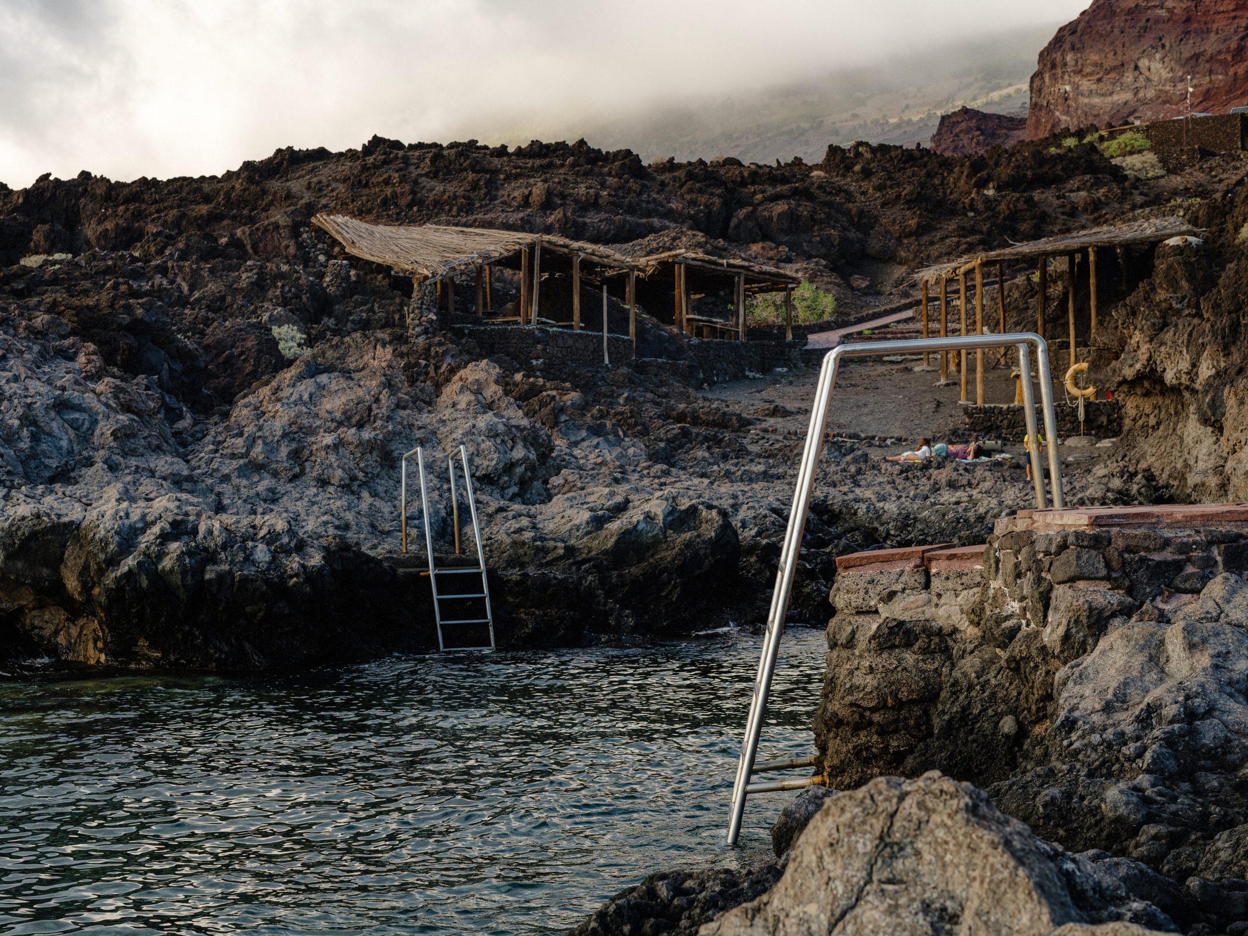 A rocky cove dotted with steel stepladders and small wooden shelters.