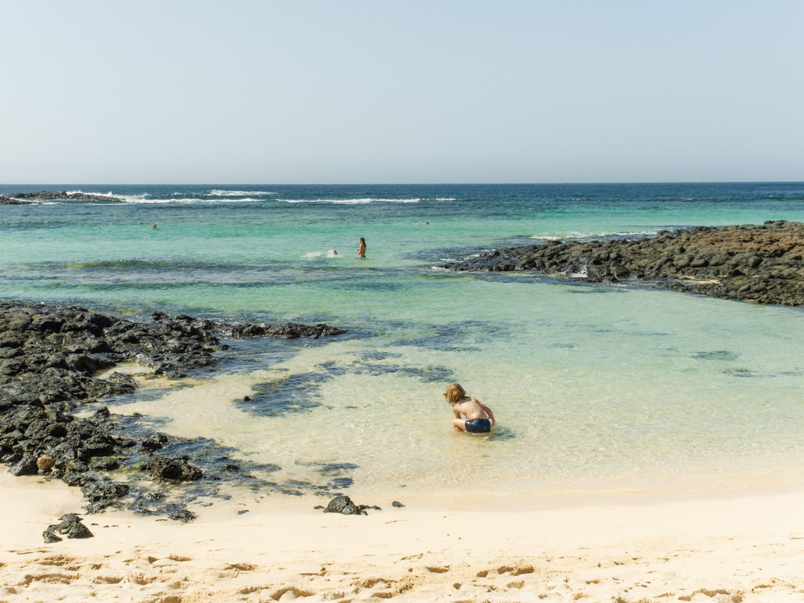 A cove of shallow water with a child playing on Fuerteventura, Canary Islands