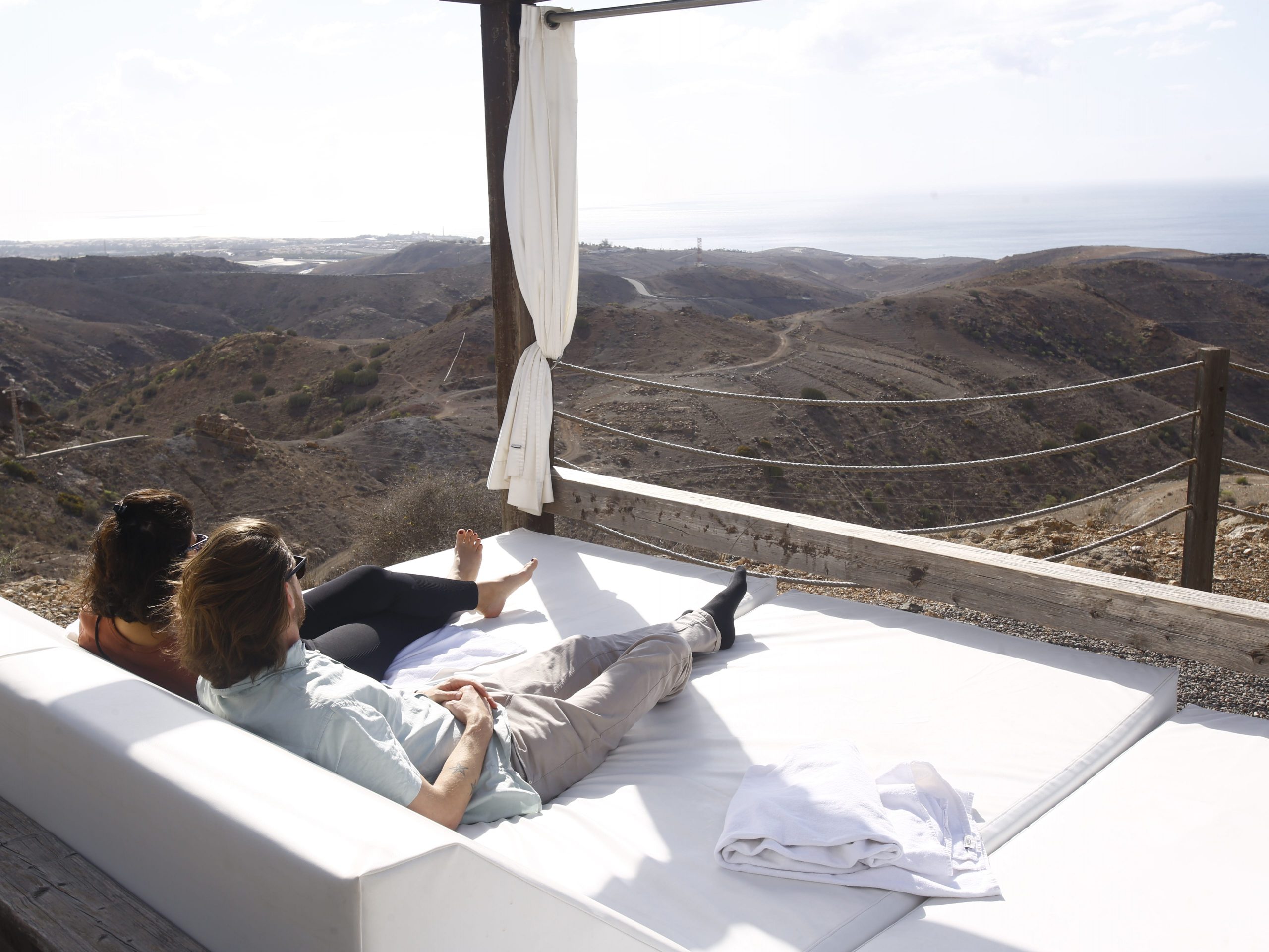 A couple on a bed overlooking a desert and mountain landscape in the Canary Islands