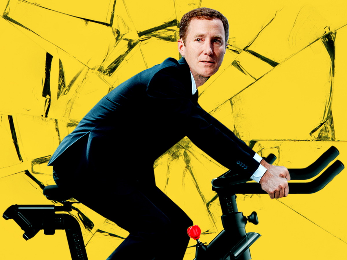 An image of Peloton CEO John Foley looking nervous on an e-bike with a shattered glass texture in the background.