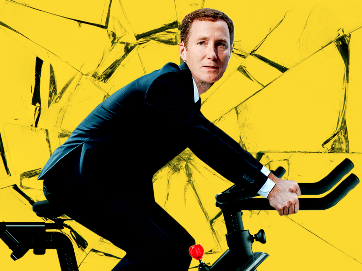 An image of Peloton CEO John Foley looking nervous on an e-bike with a shattered glass texture in the background.