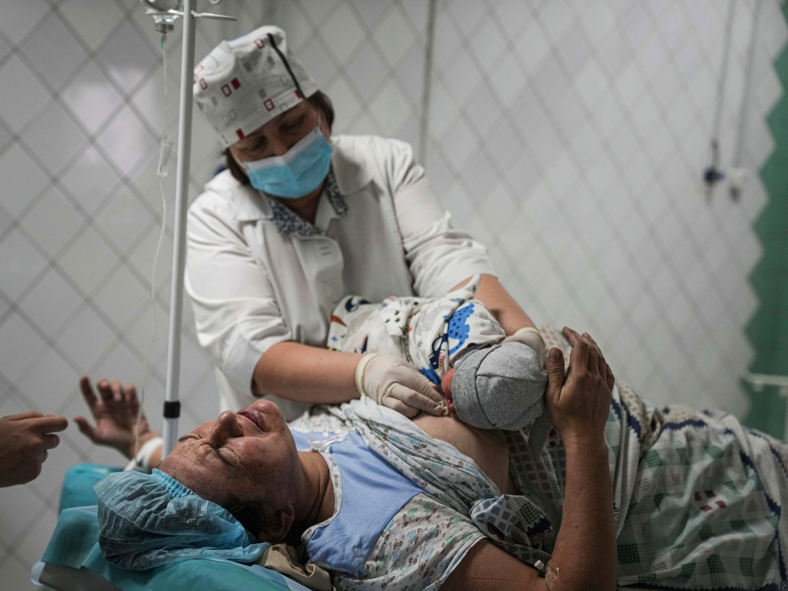 A maternity nurse shows a newborn baby to a woman who gave birth at a maternity hospital converted into a medical ward in Mariupol, Ukraine, Tuesday, March 1, 2022.