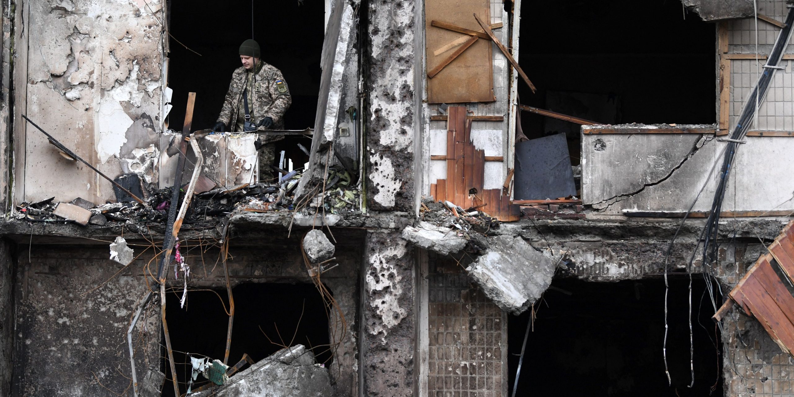 A Ukrainian serviceman is seen in the window of a damaged residential building at Koshytsa Street, a suburb of the Ukrainian capital Kyiv, where a military shell allegedly hit, on February 25, 2022