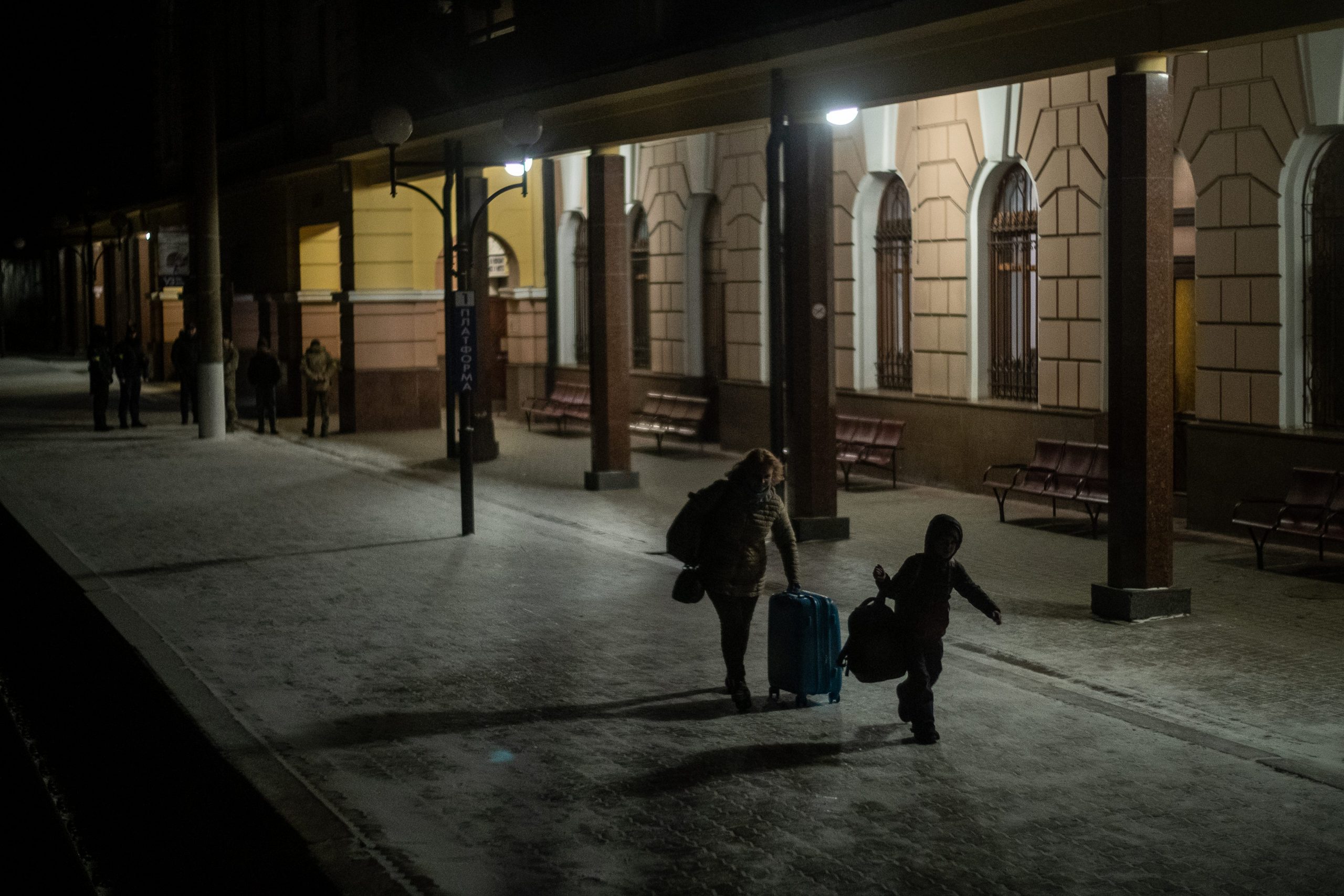 A woman and a child walk along a platform at a train station.