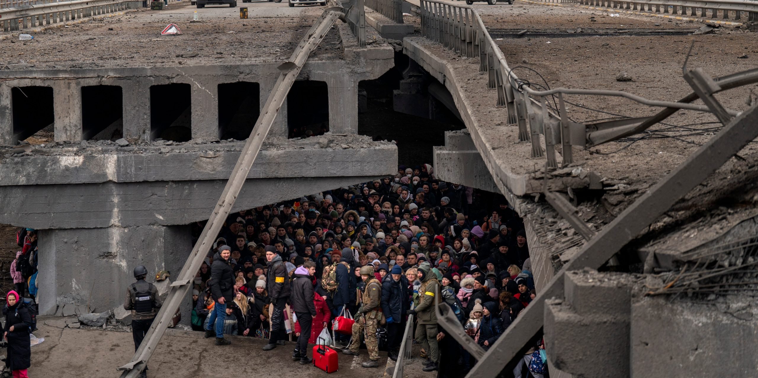 Ukrainians crowd under a destroyed bridge as they try to flee across the Irpin River in the outskirts of Kyiv, Ukraine, Saturday, March 5, 2022.