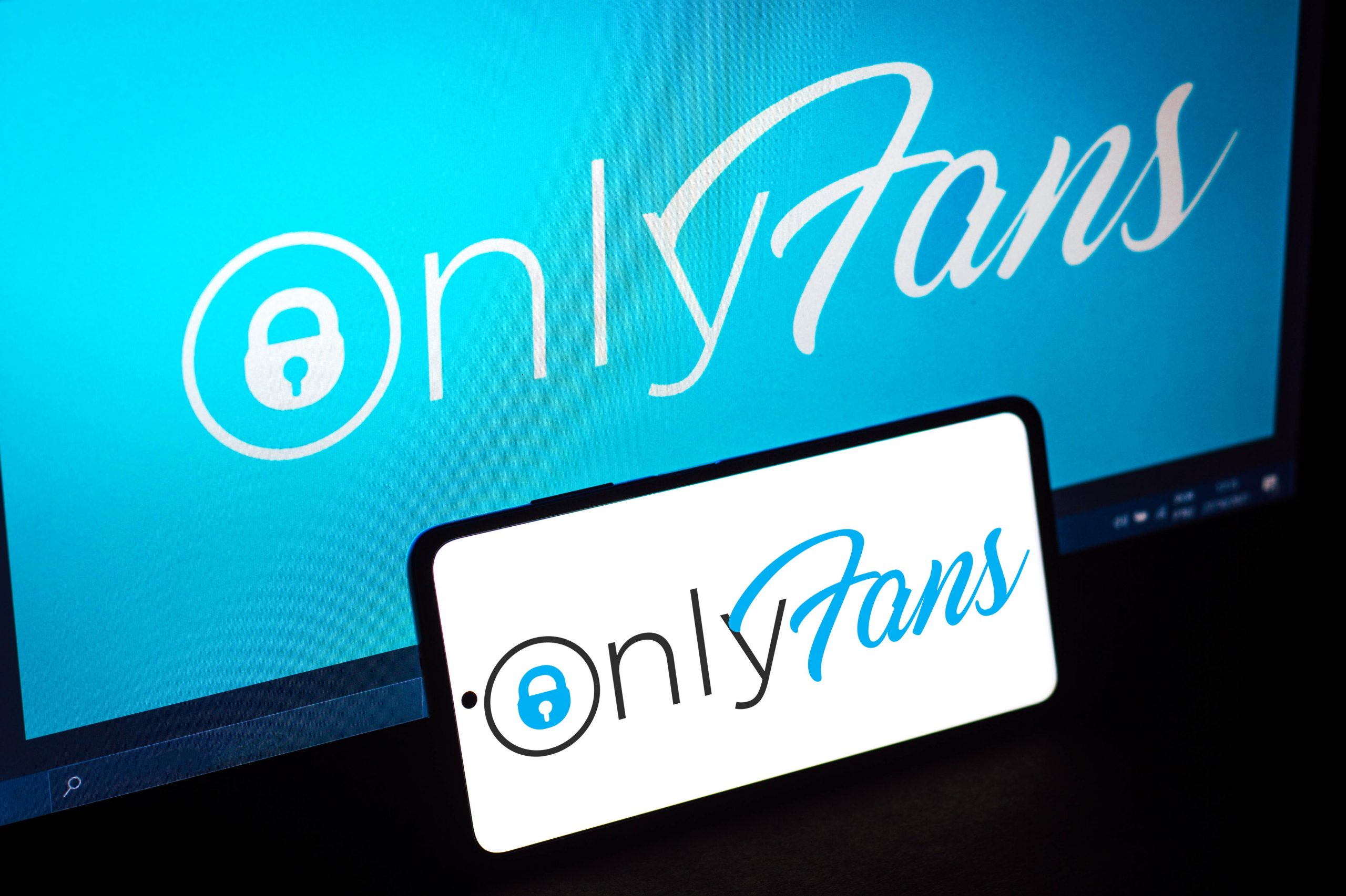 Computer and phone with OnlyFans logo displayed.