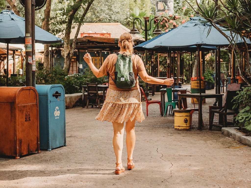 The writer wearing a neutral-colored skirt outfit, in tropical location with small backpack