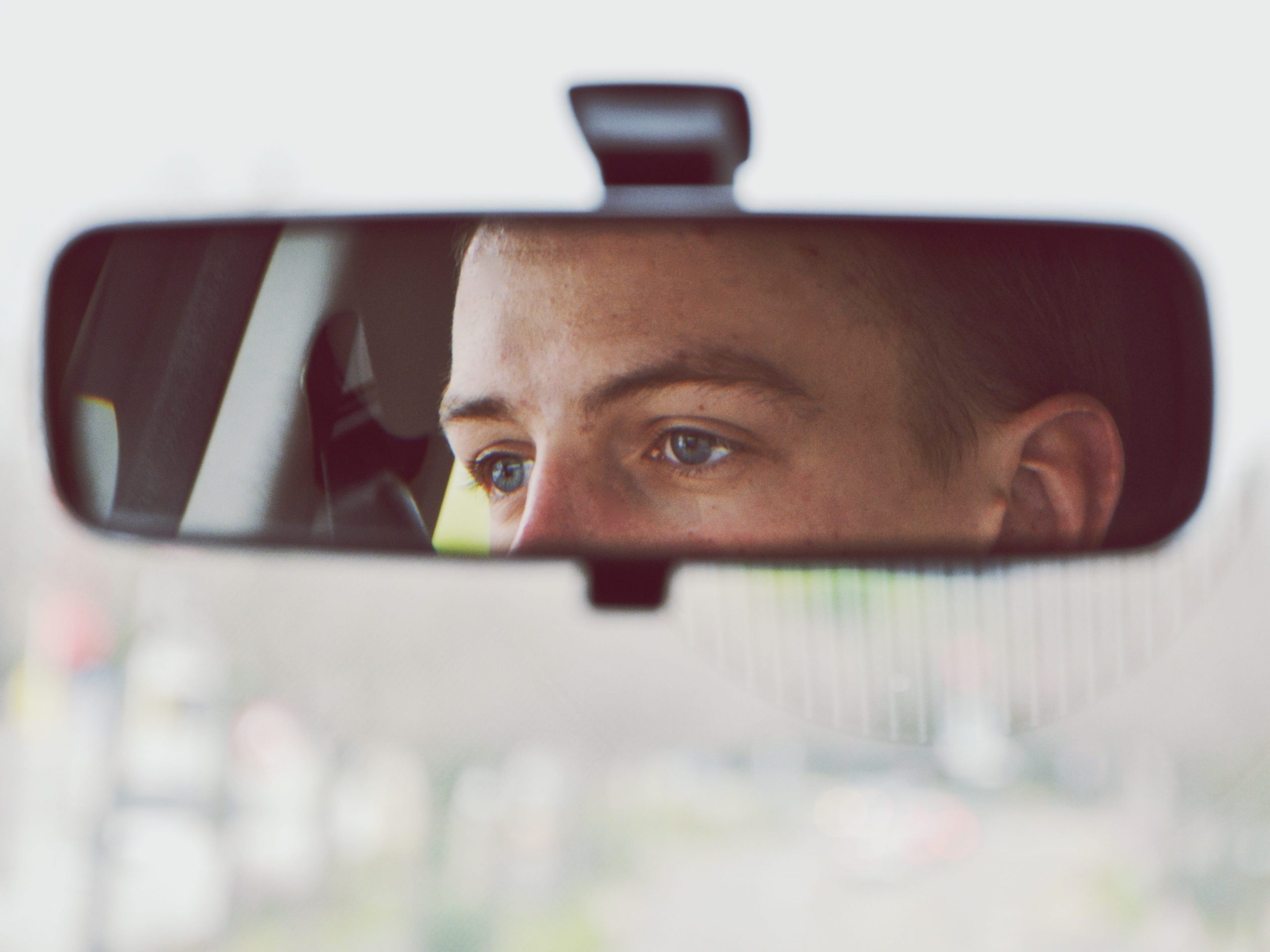 Reflection Of Man In Car On Rear-View Mirror