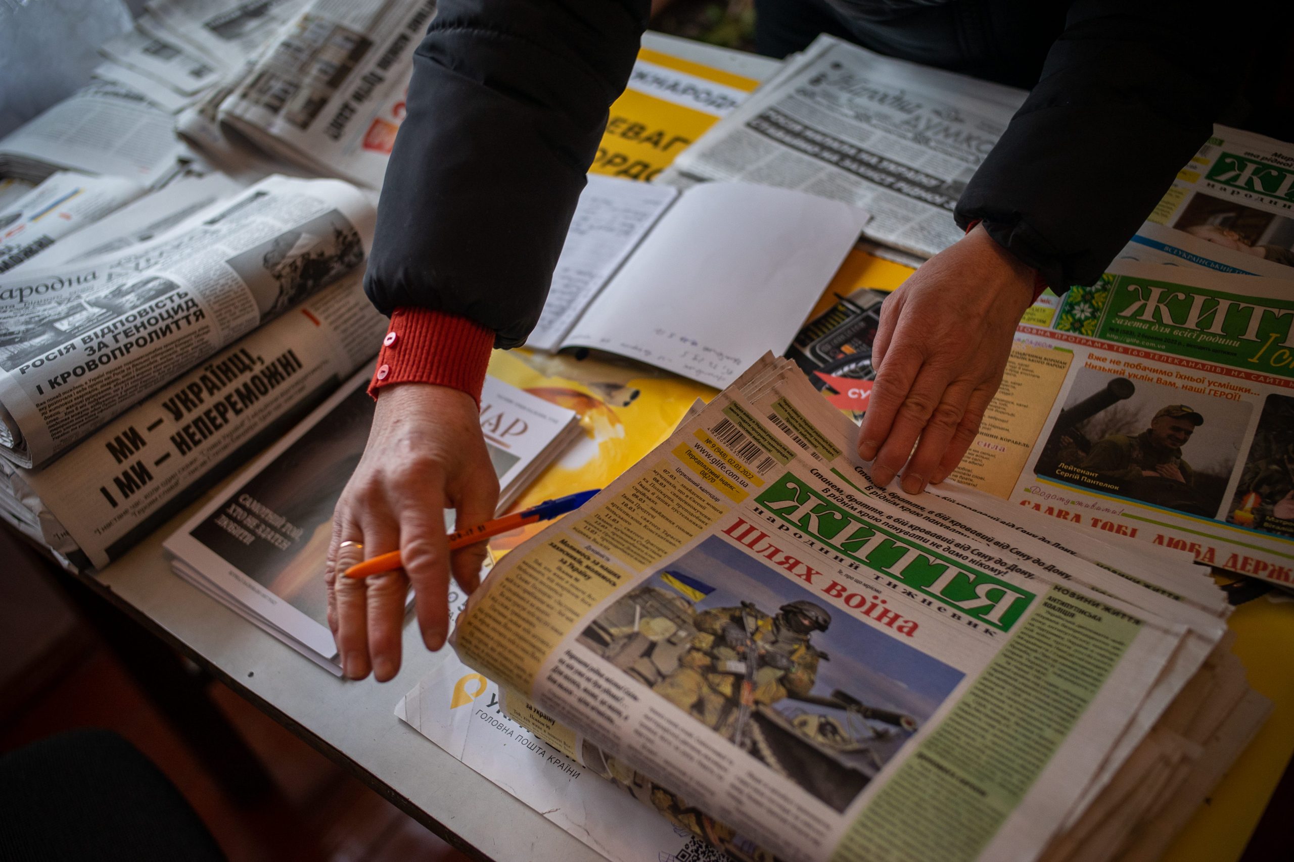 Woman's hands sit on a Ukrainian newspaper.