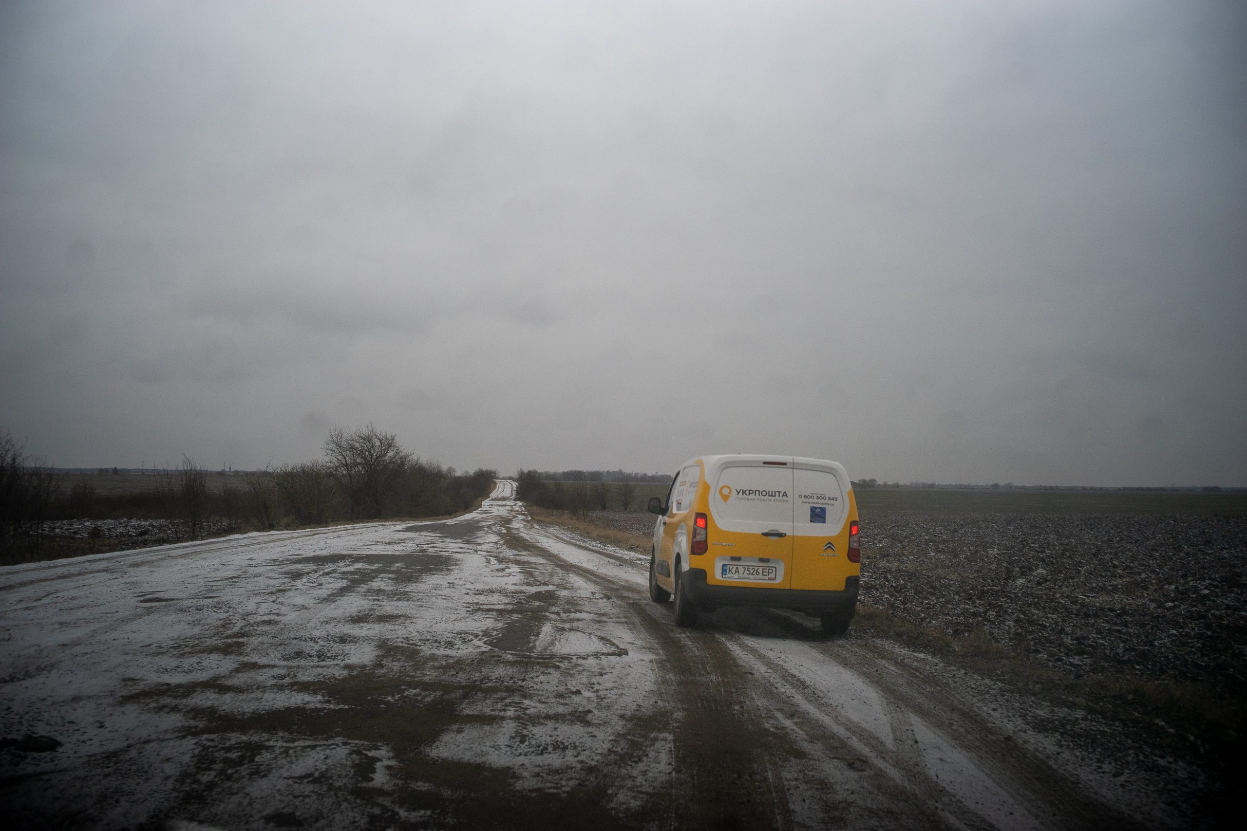 A white and yellow van drives down a snowy road in Ukraine