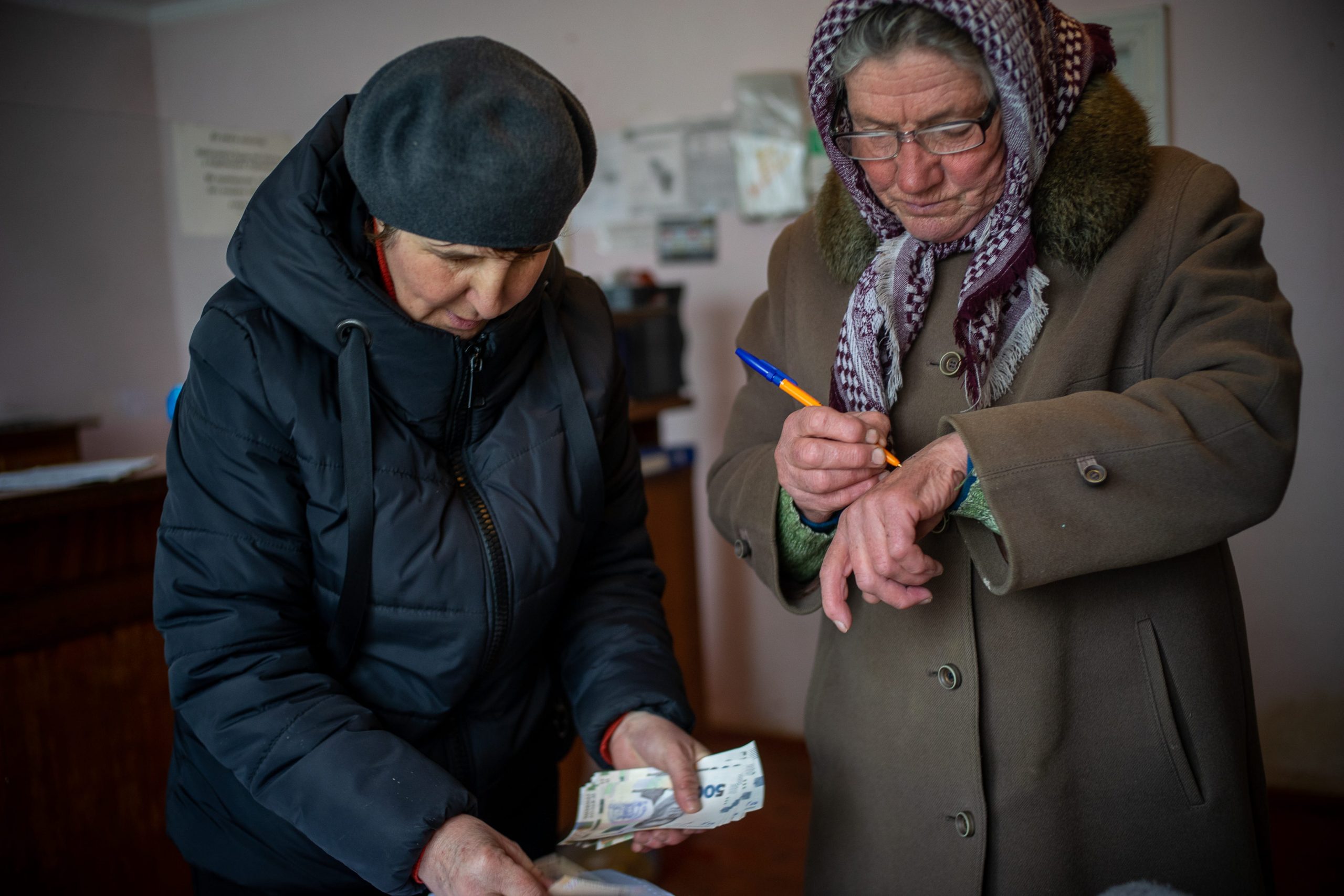 Two women sort and calculate money.