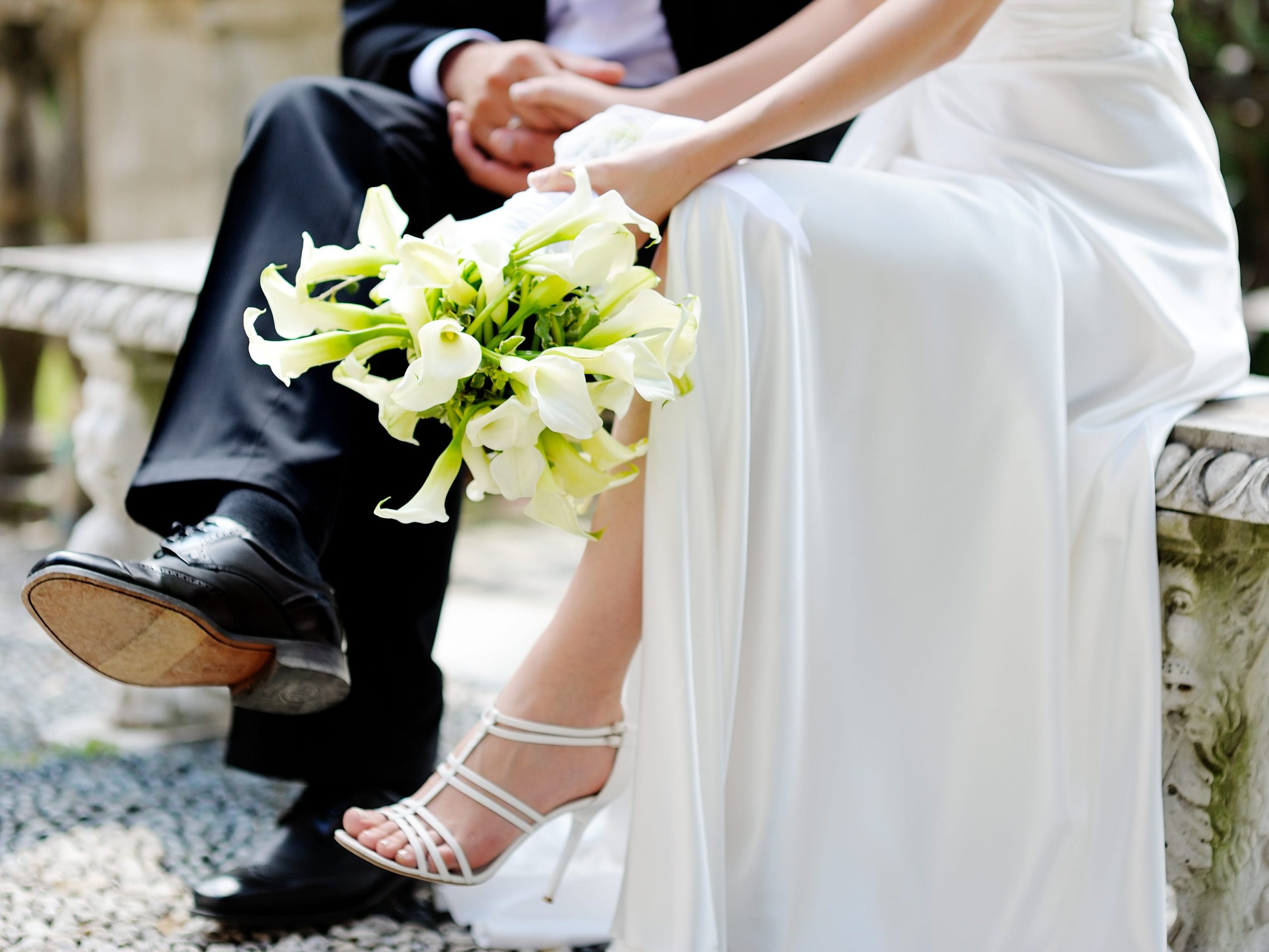 A bride and groom sitting on a bench.
