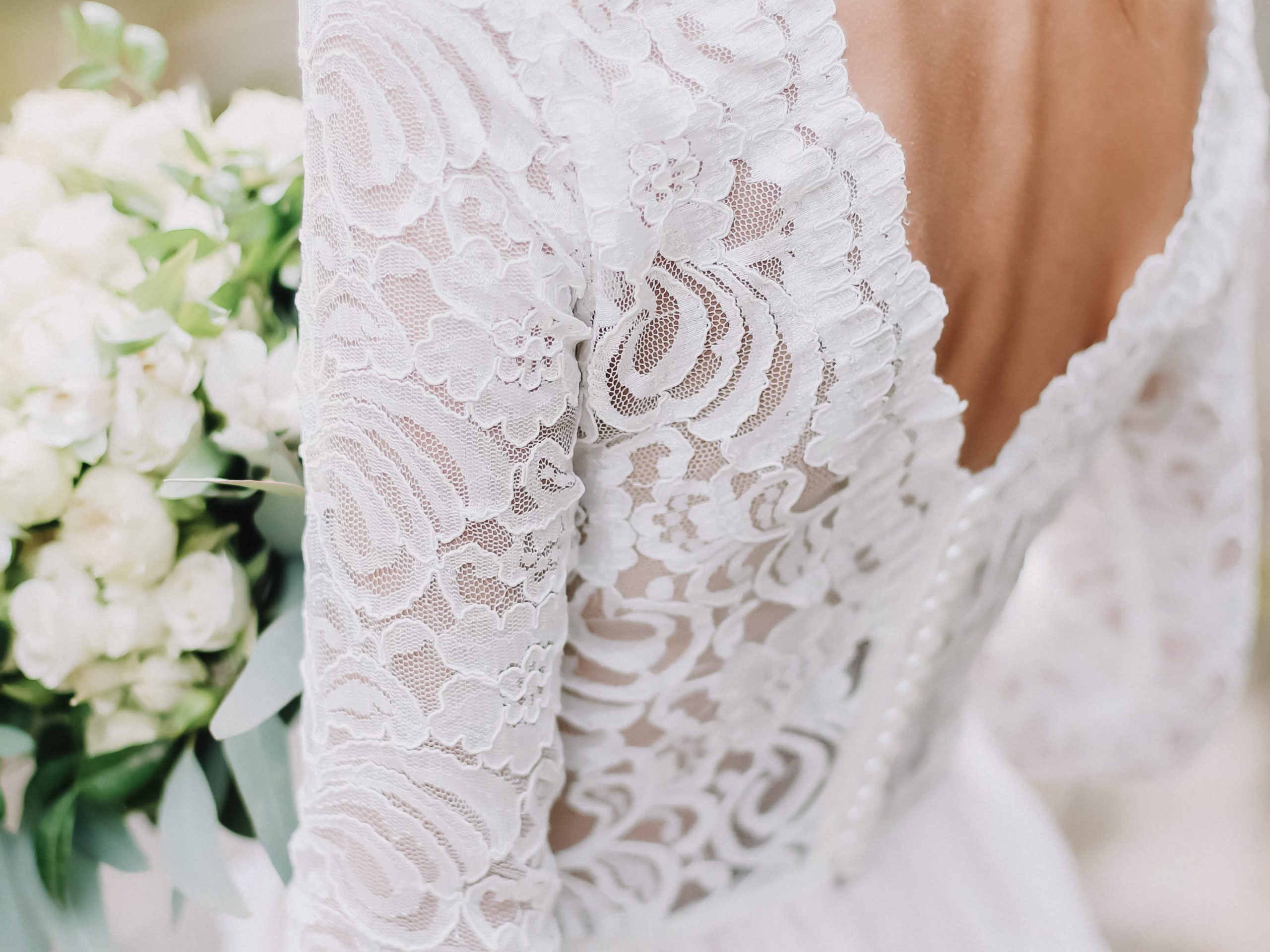 Bride in lace wedding gown with white bouquet of flowers