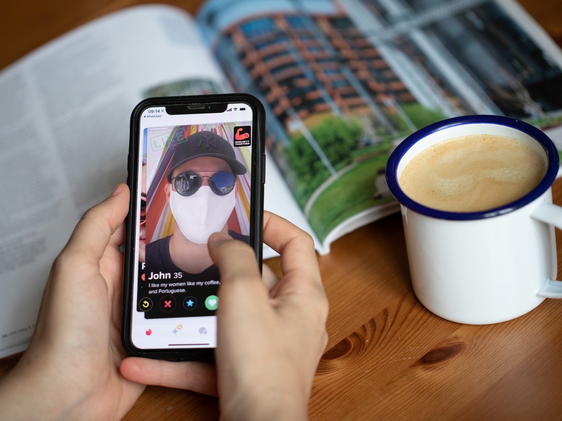 A person holding a phone swipes through the Tinder app, which shows a man wearing a mask and sunglasses