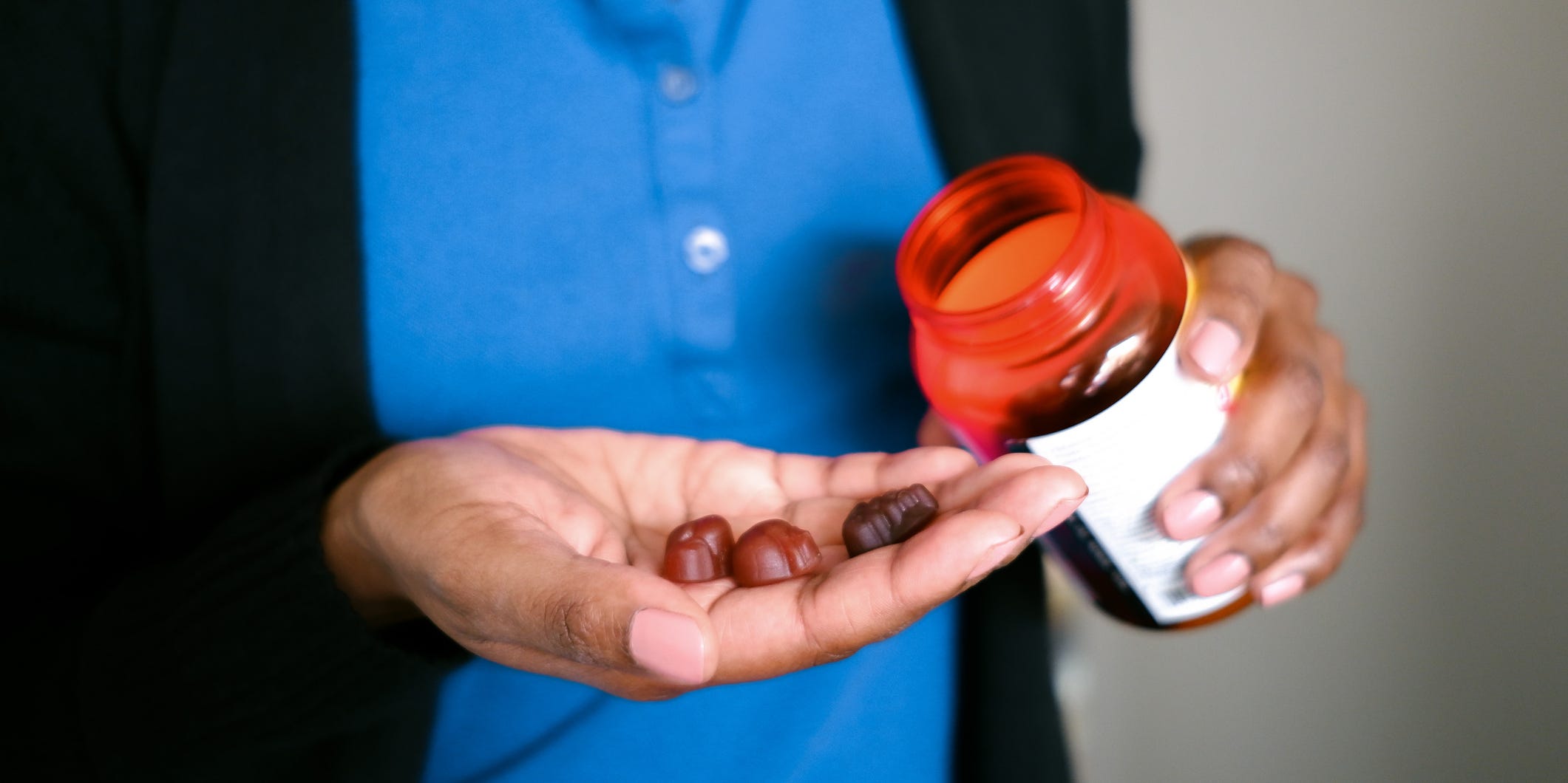 A person holds gummy supplements in their hand.