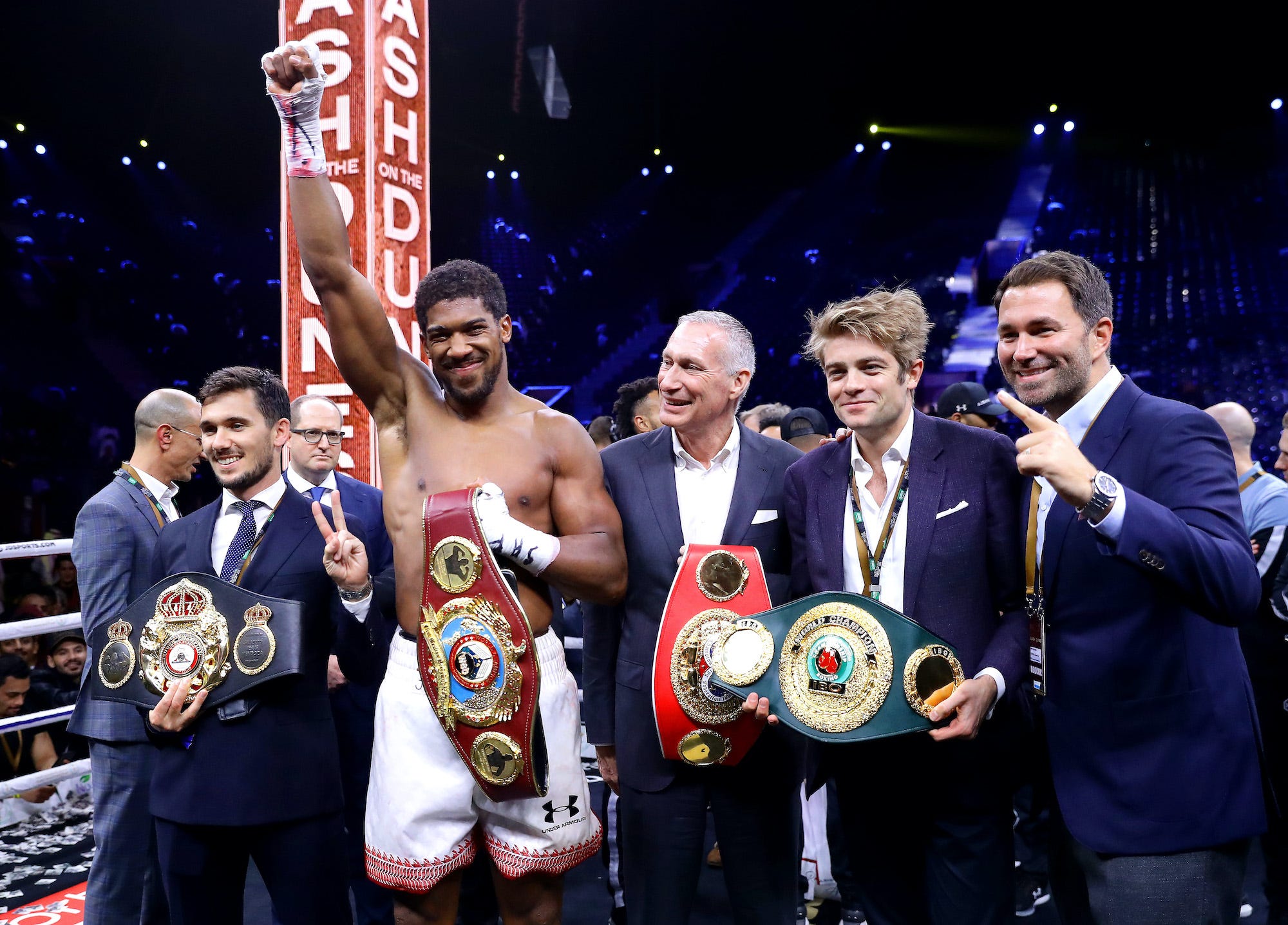 Anthony Joshua celebrates reclaiming his world titles in Saudi Arabia, alongside DAZN executives.