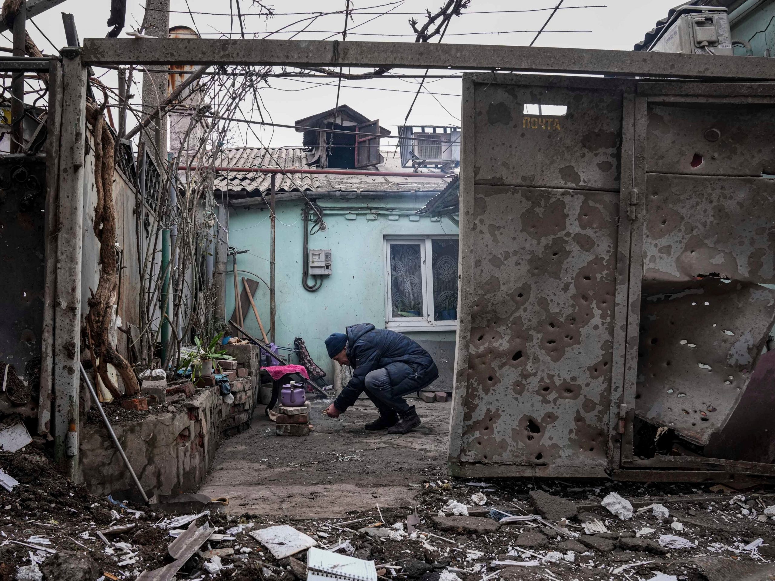 A man lights a fire under the kettle in a yard of an apartment building hit by shelling in Mariupol, Ukraine, Monday, March 7, 2022.