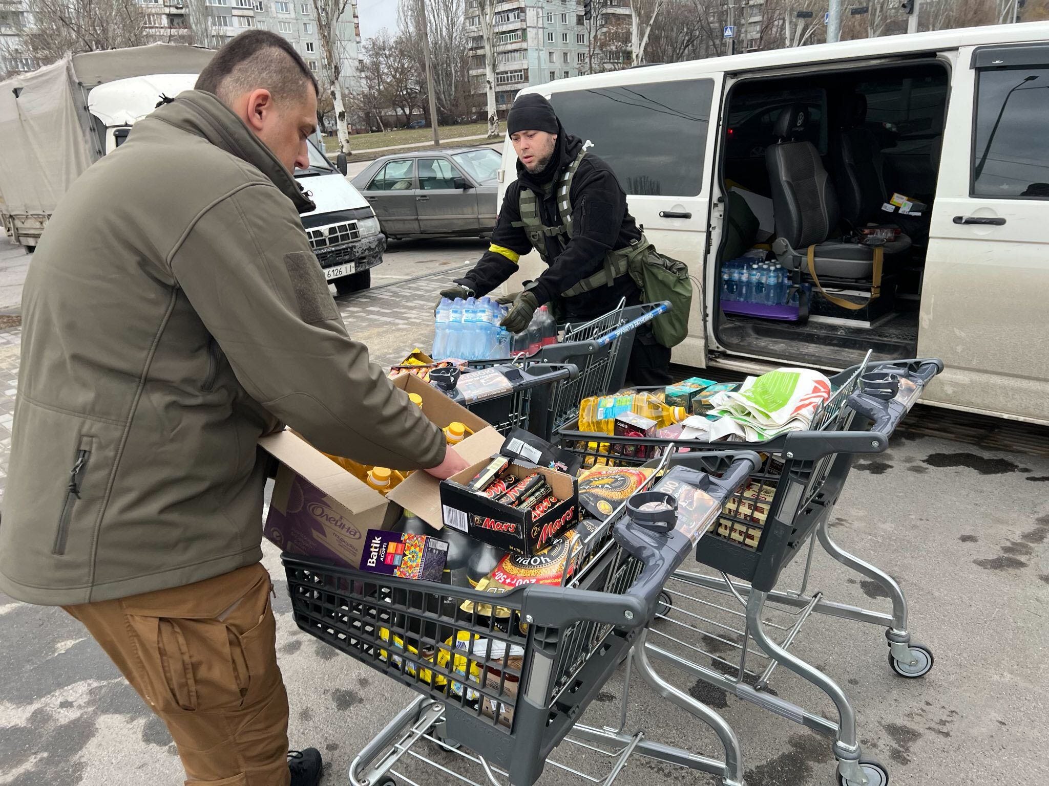 Two Ukrainian volunteers unpack shopping carts full of supplies.