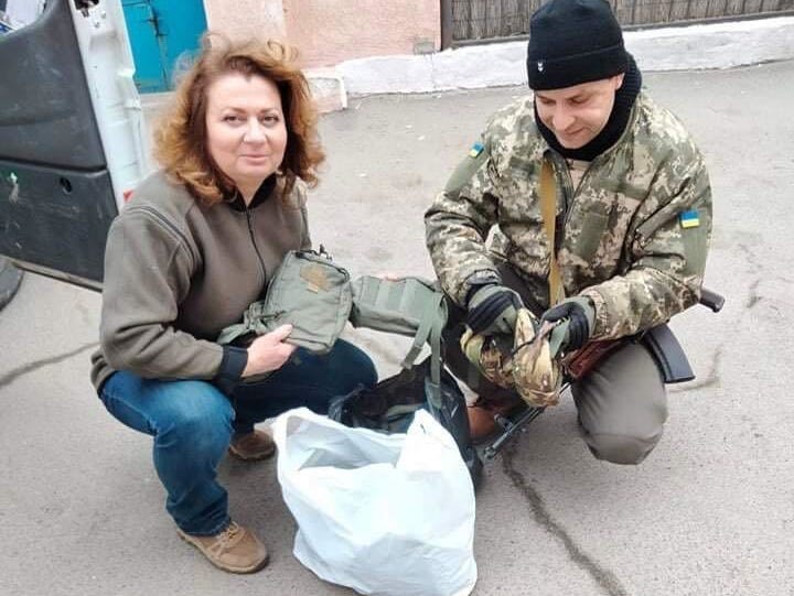 Two Ukrainian volunteers pose for the camera with supplies for the Territorial Defense Forces.