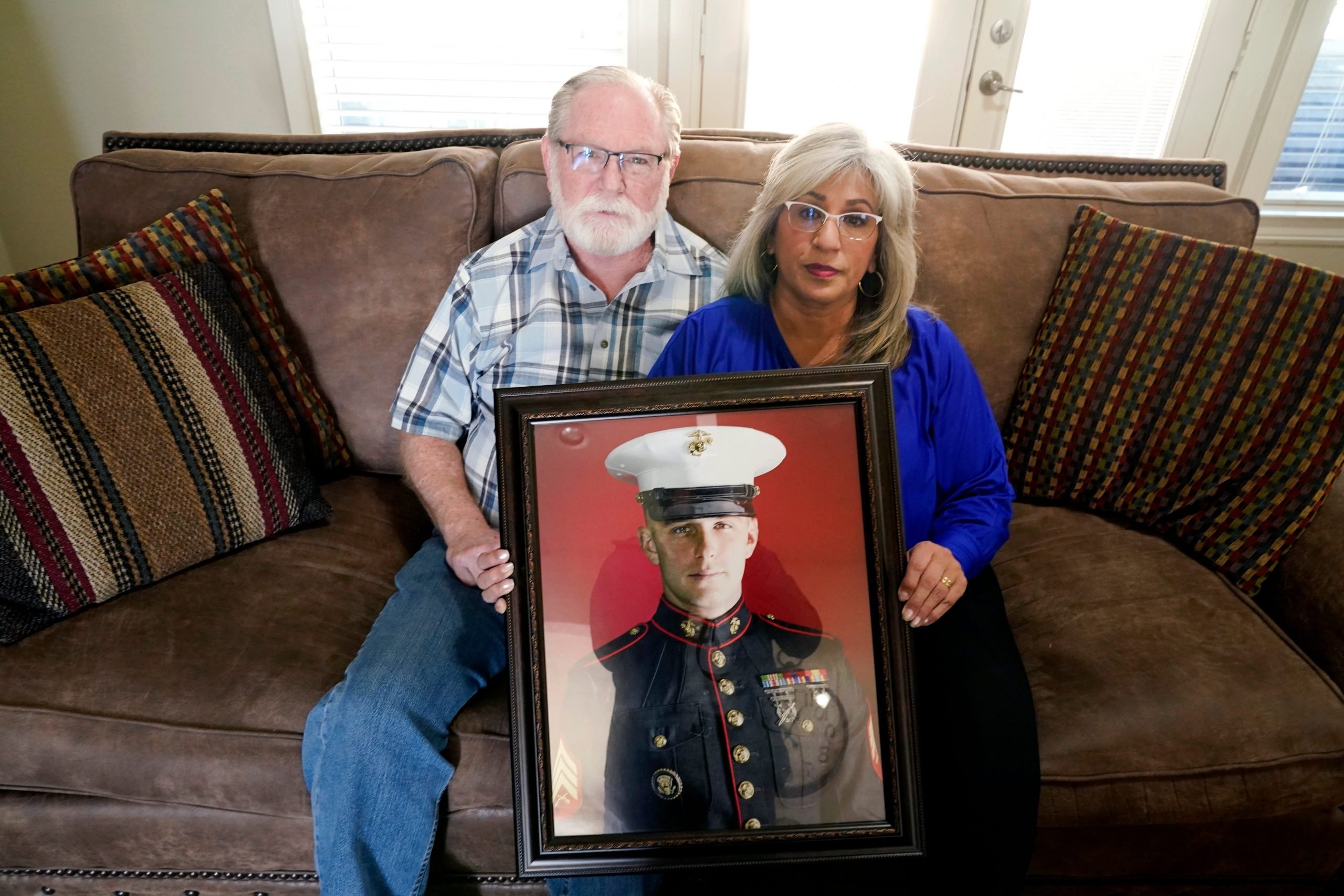 Joey and Paula Reed pose for a photo with a portrait of their son Marine veteran and Russian prisoner Trevor Reed at their home in Fort Worth, Texas, Feb. 15, 2022.