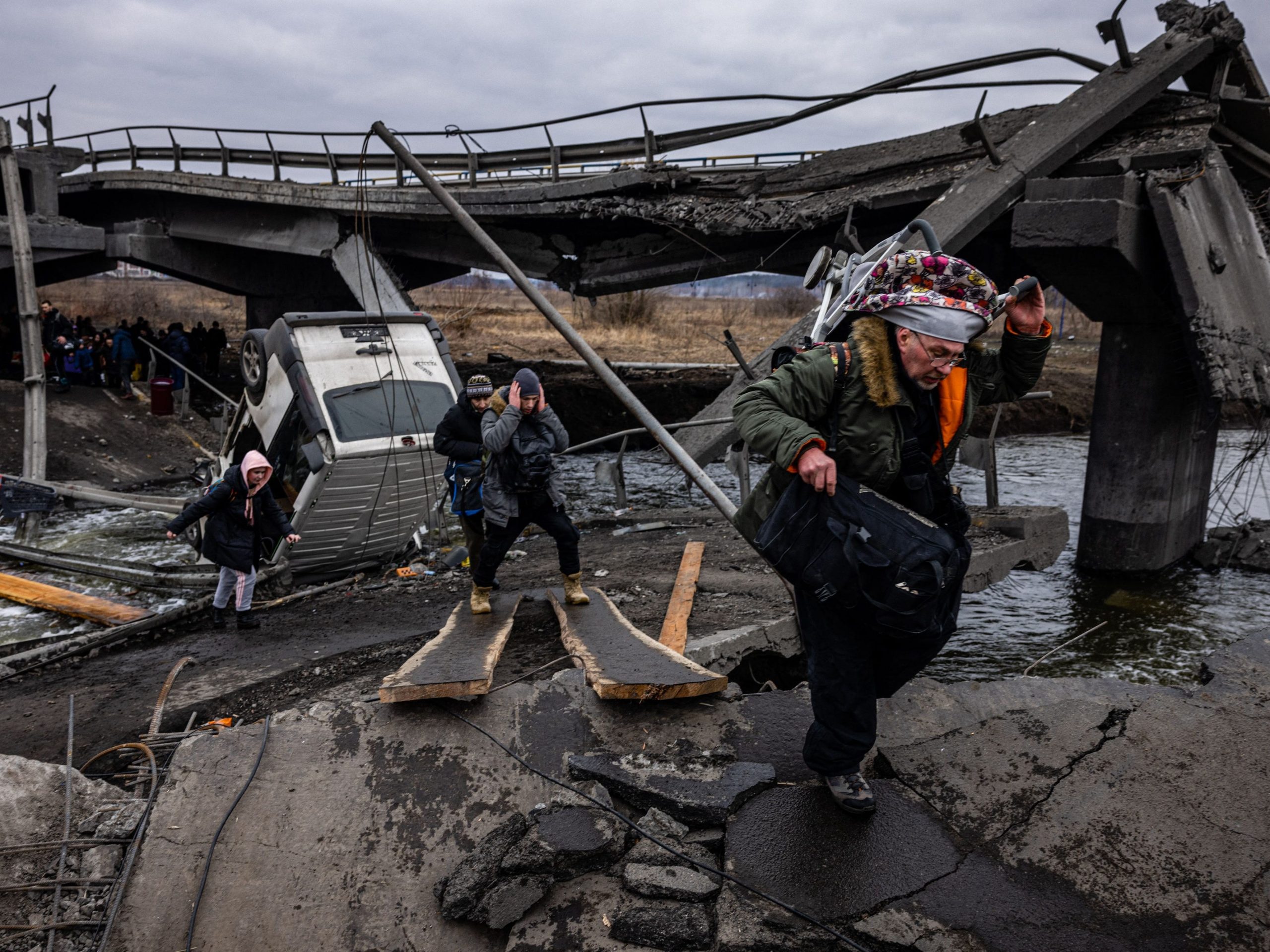 Evacuees cross a destroyed bridge as they flee the city of Irpin, northwest of Kyiv, on March 7, 2022.