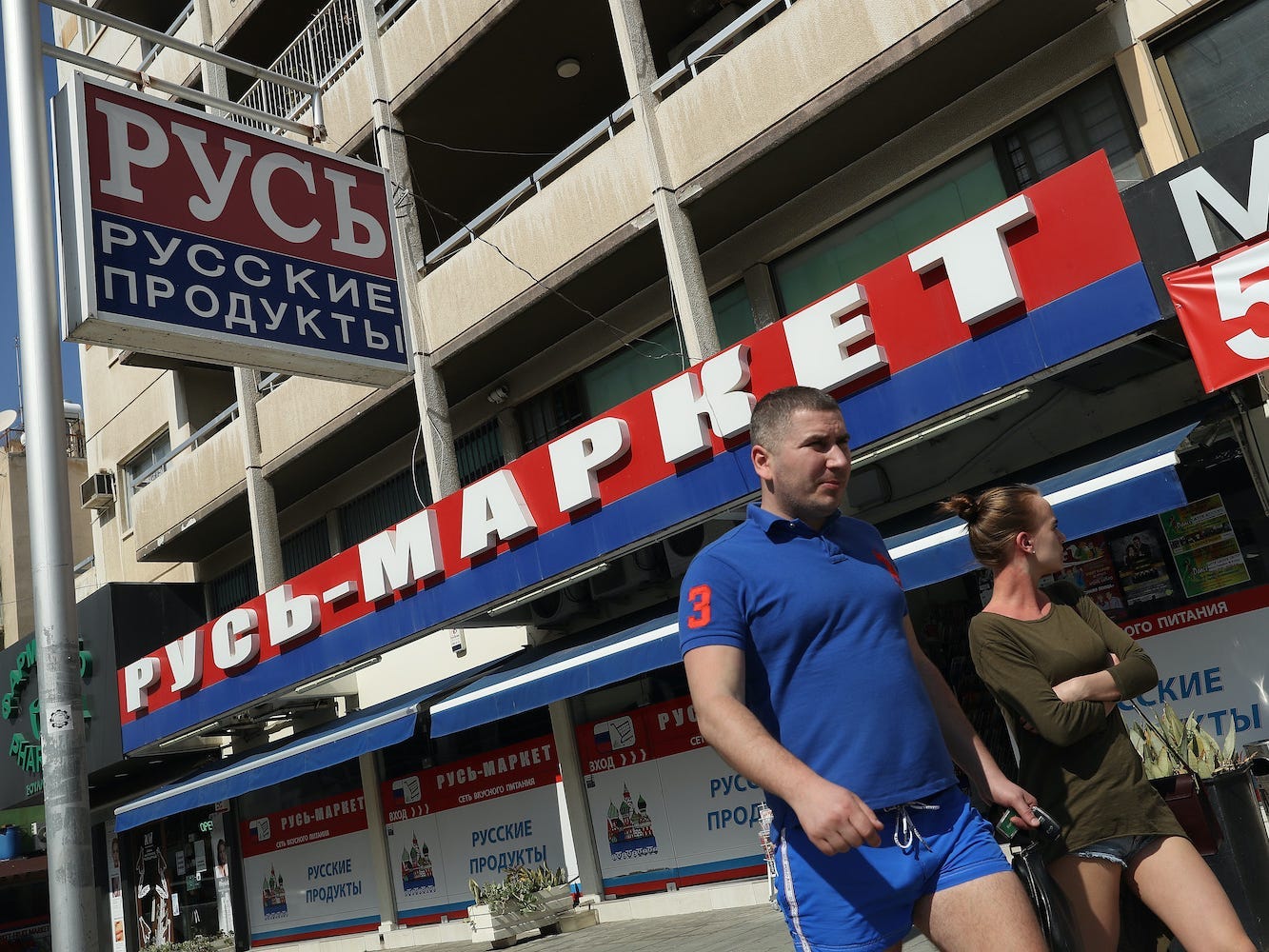 Een koppel loopt langs een Russische supermarkt in Limassol, Cyprus.