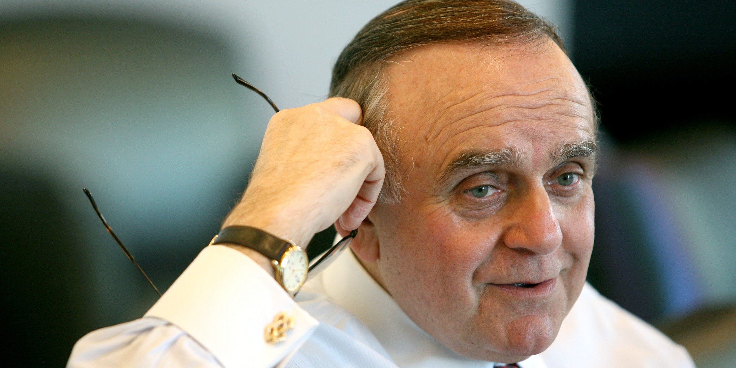 Leon Cooperman holding his glasses up to his right temple.
