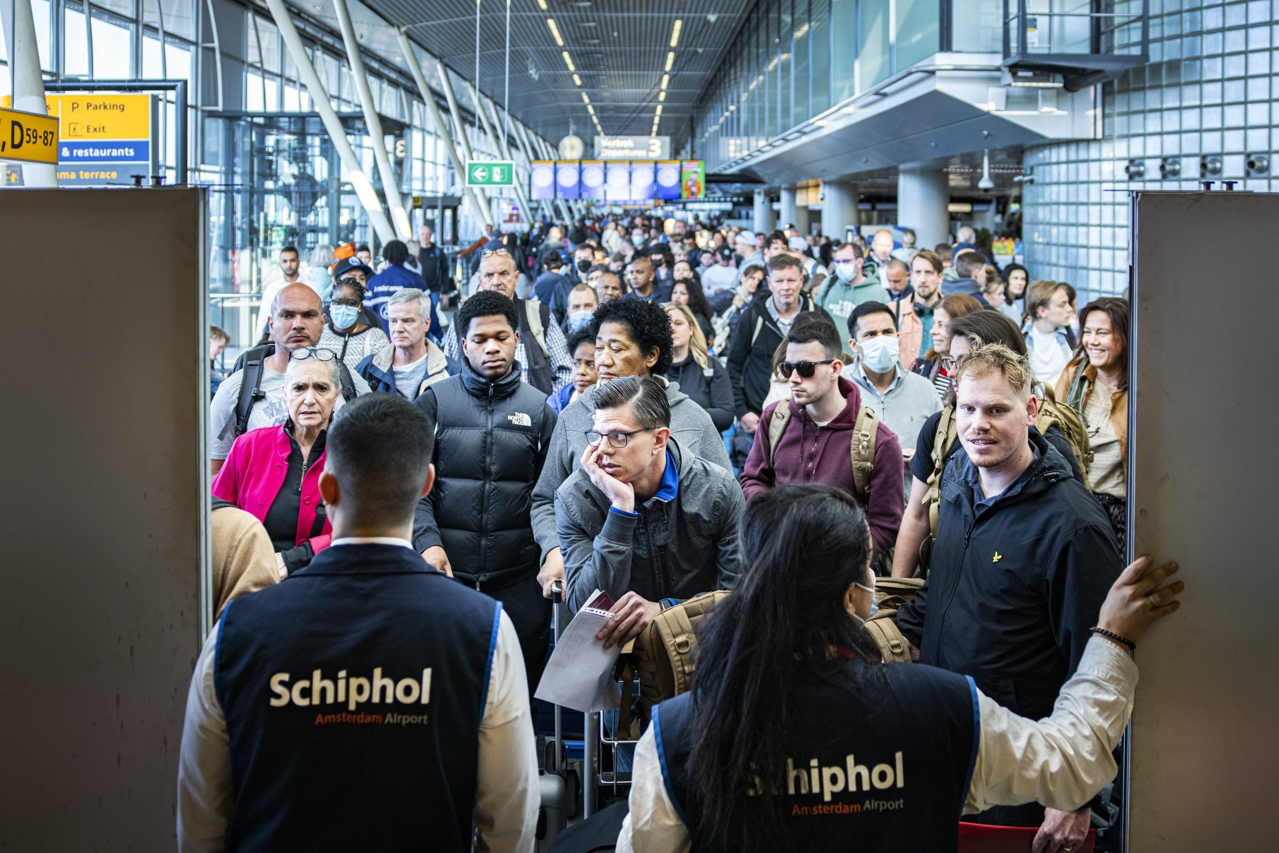 Reizigers in een volle vertrekhal op Schiphol. 