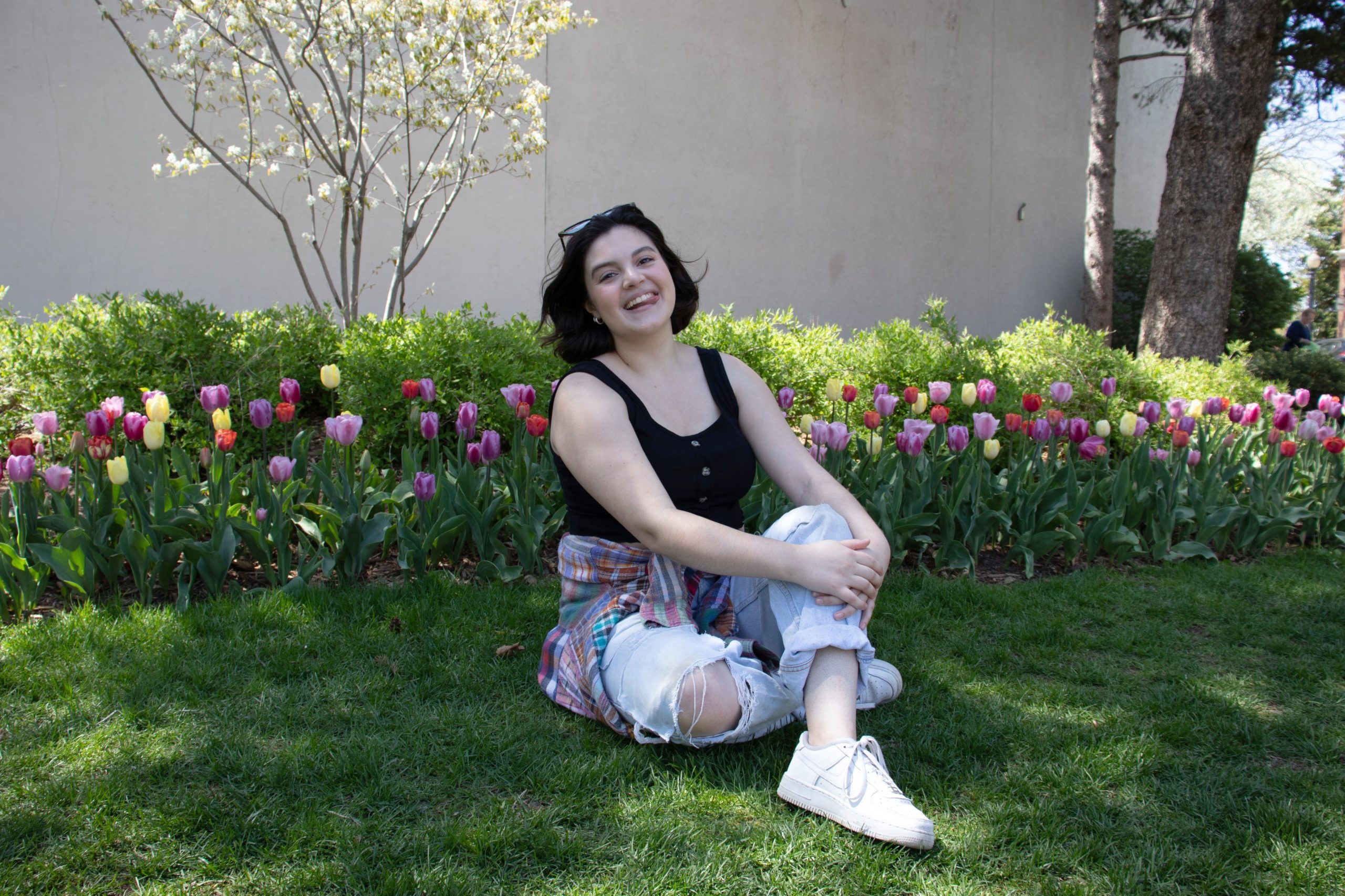Insiders Gabi Stevenson poseert lachend voor tulpen in een zwarte top en spijkerbroek.  