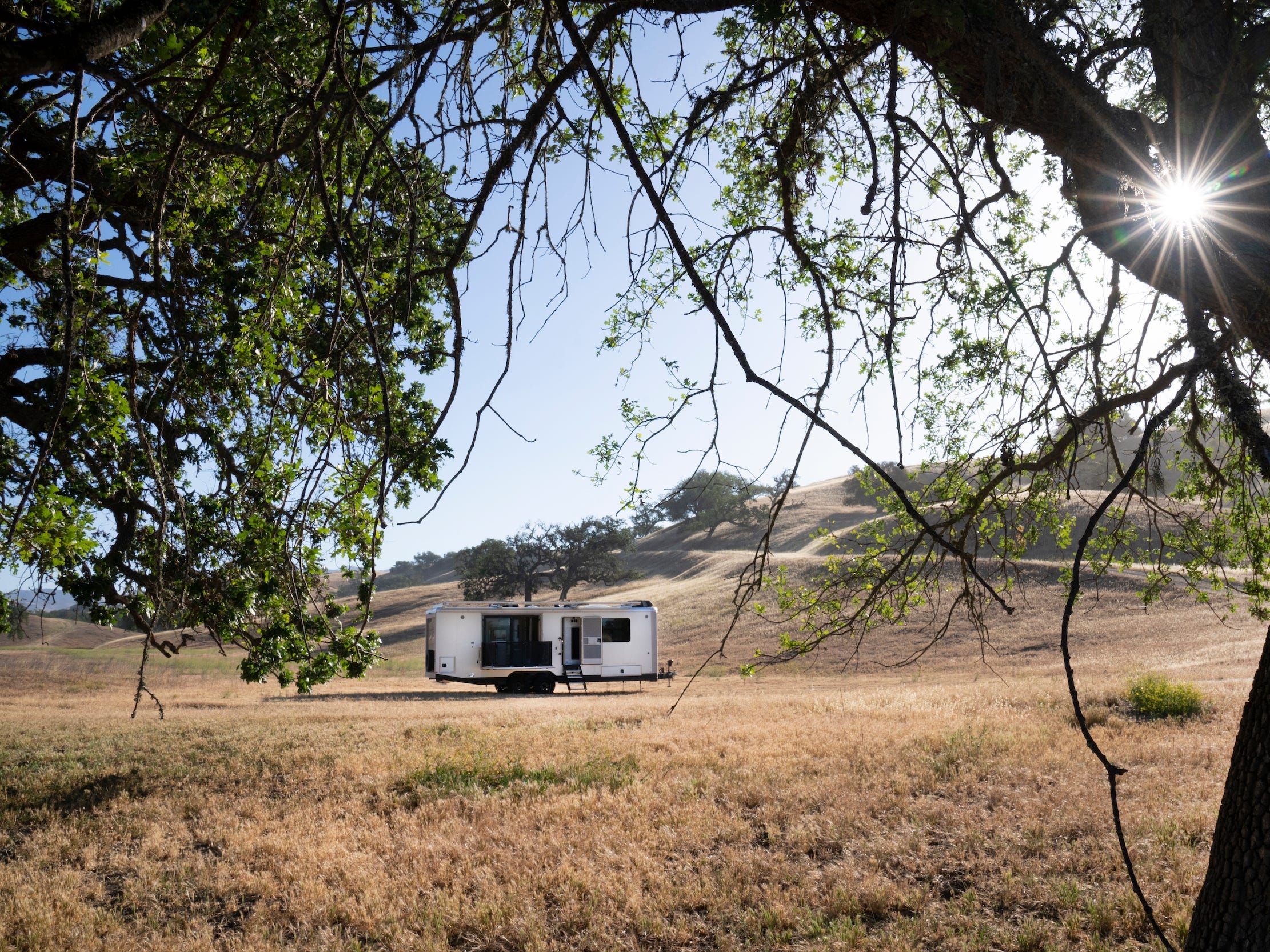 Het exterieur van de reis trailer zoals het op een bruin veld staat.