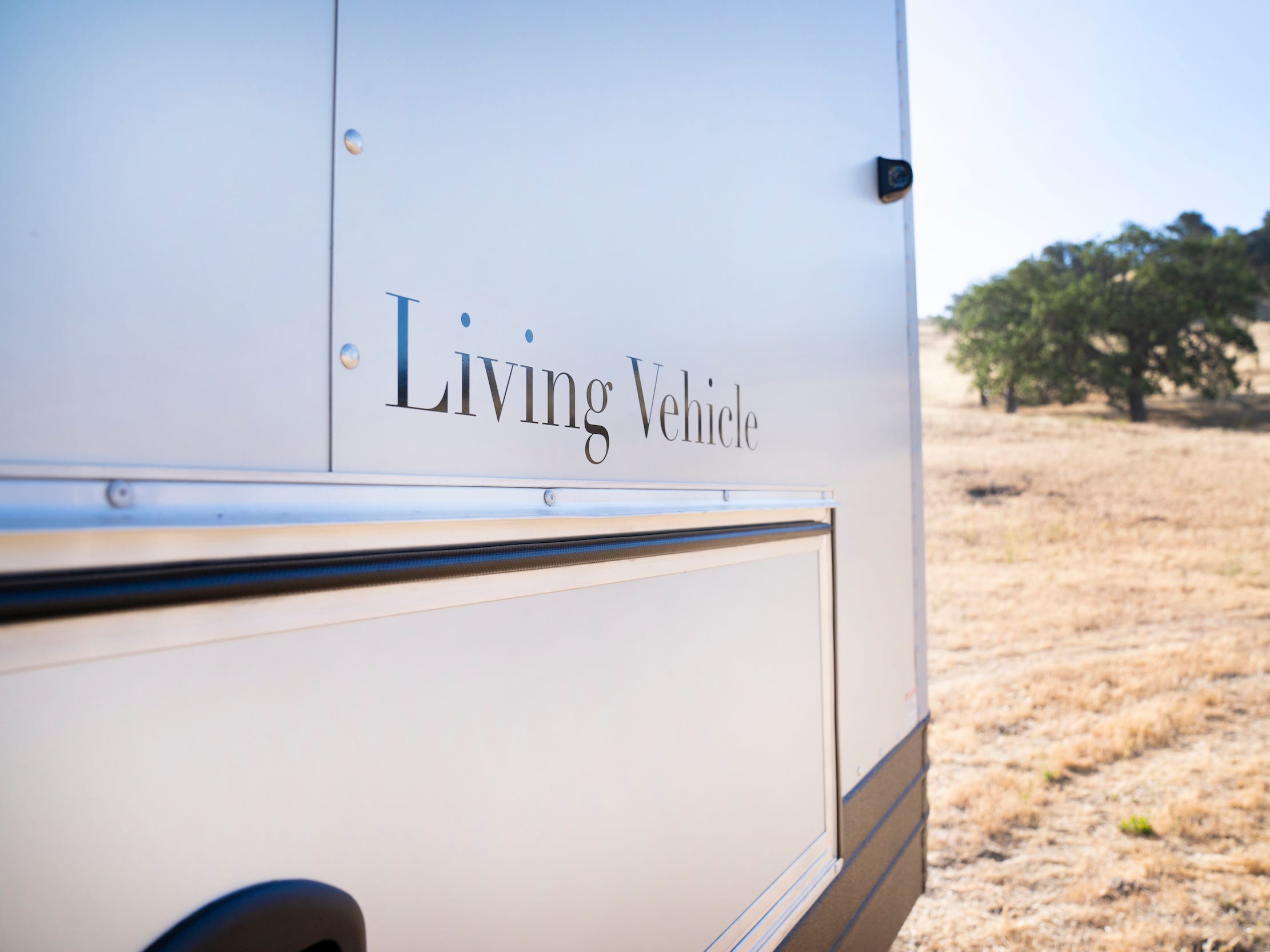 Een close up van de buitenkant van de reis trailer met Living Vehicle's logo.