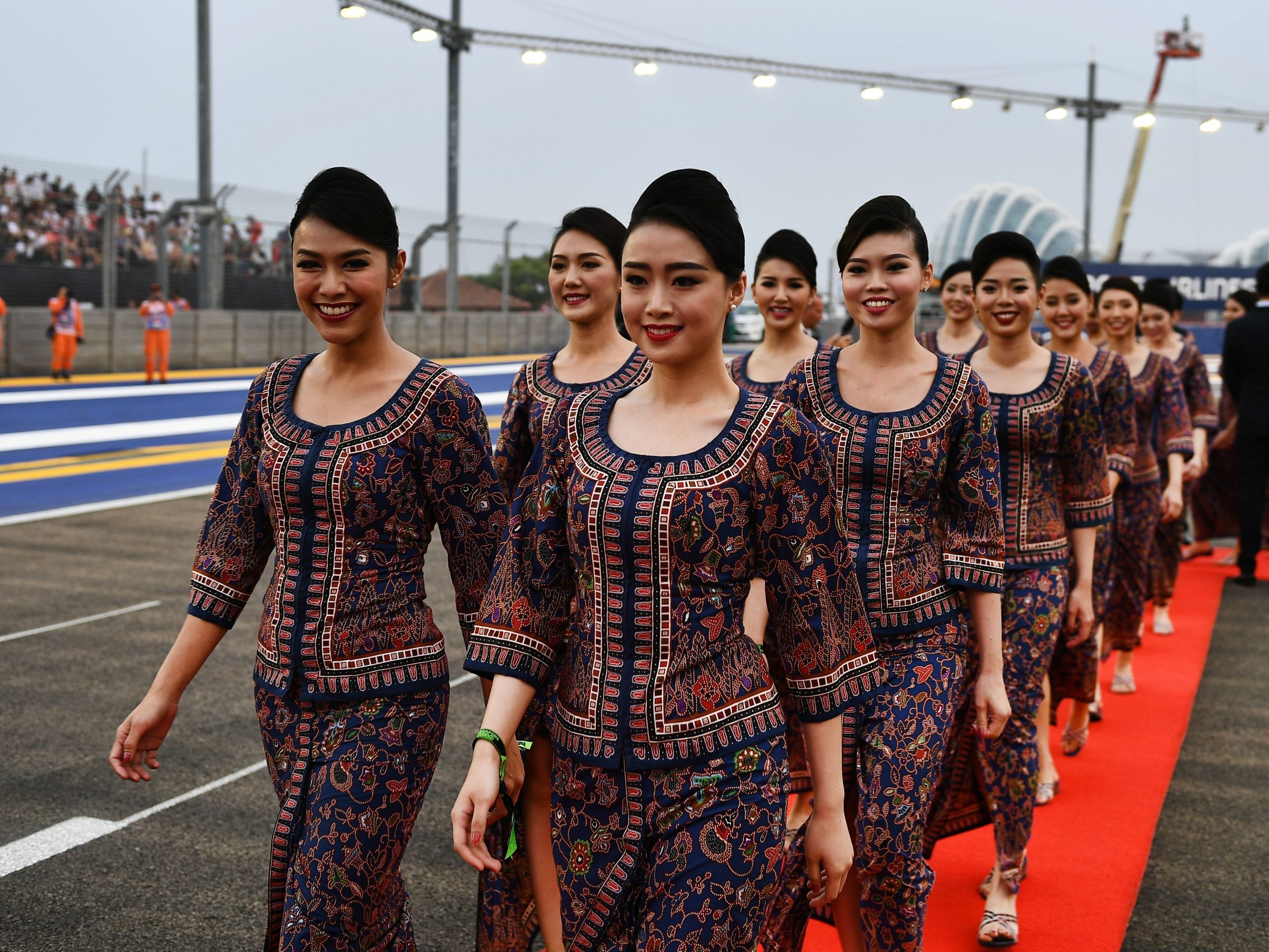 Een team van stewardessen van Singapore Airlines die over de rode loper lopen.