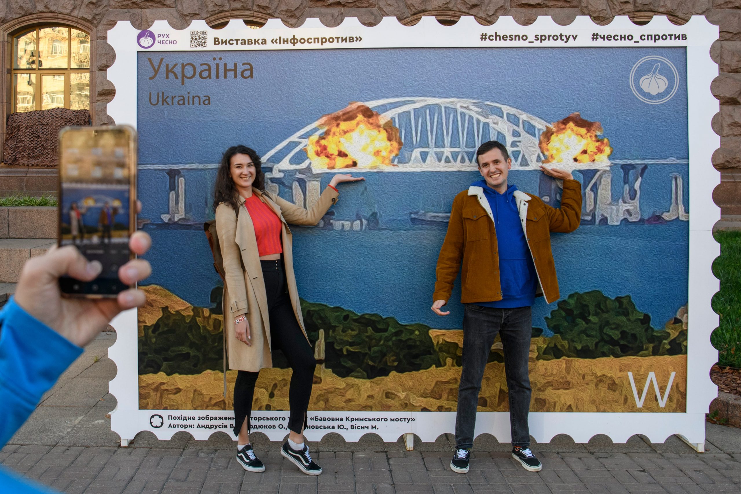 Oekraïense burgers poseren voor een levensgrote postzegel die gemaakt om de explosie op de Krimbrug te vieren. 