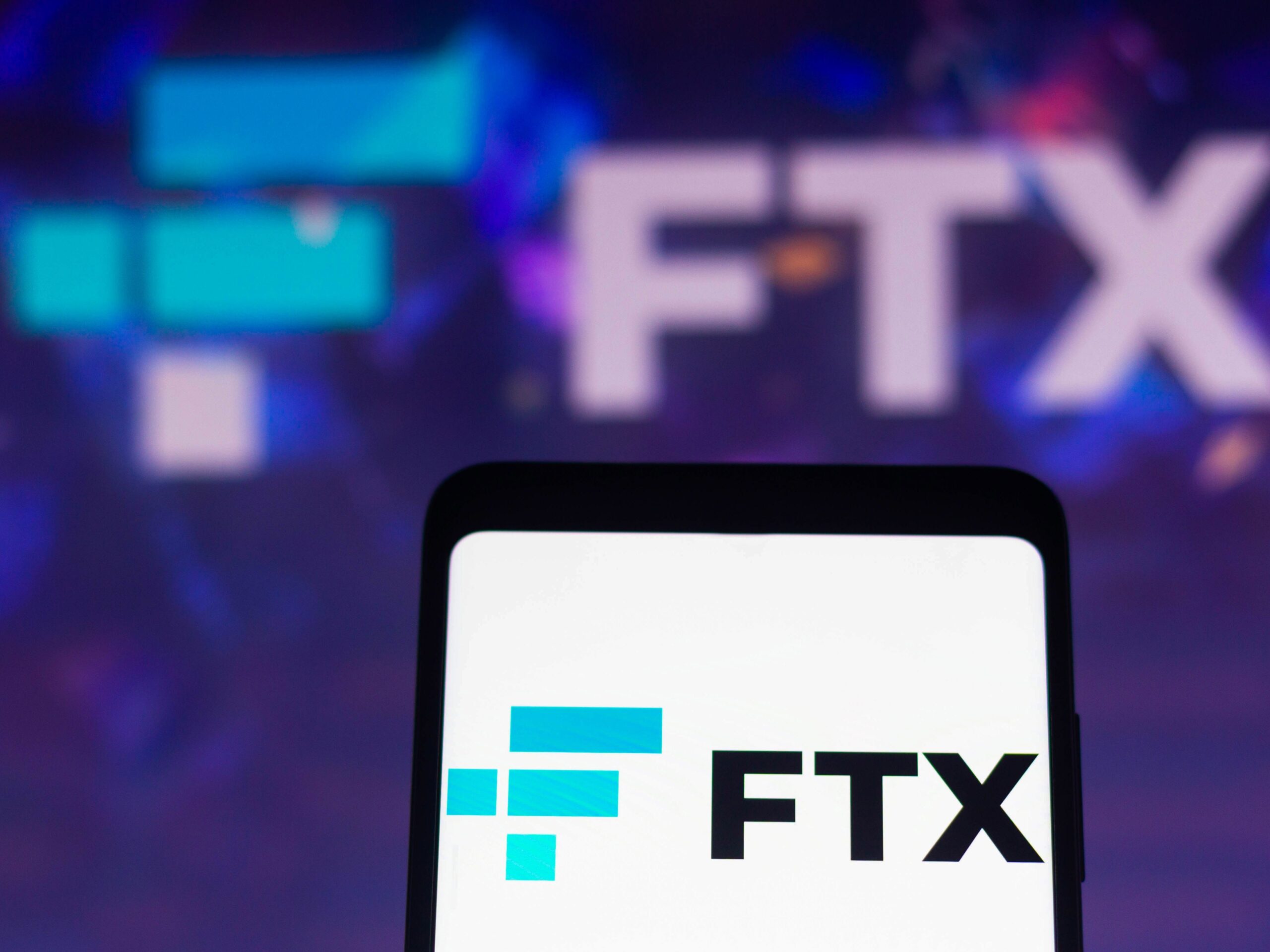 In this photo illustration, the FTX Crypto Derivatives Exchange logo is displayed on a smartphone screen and in the background.