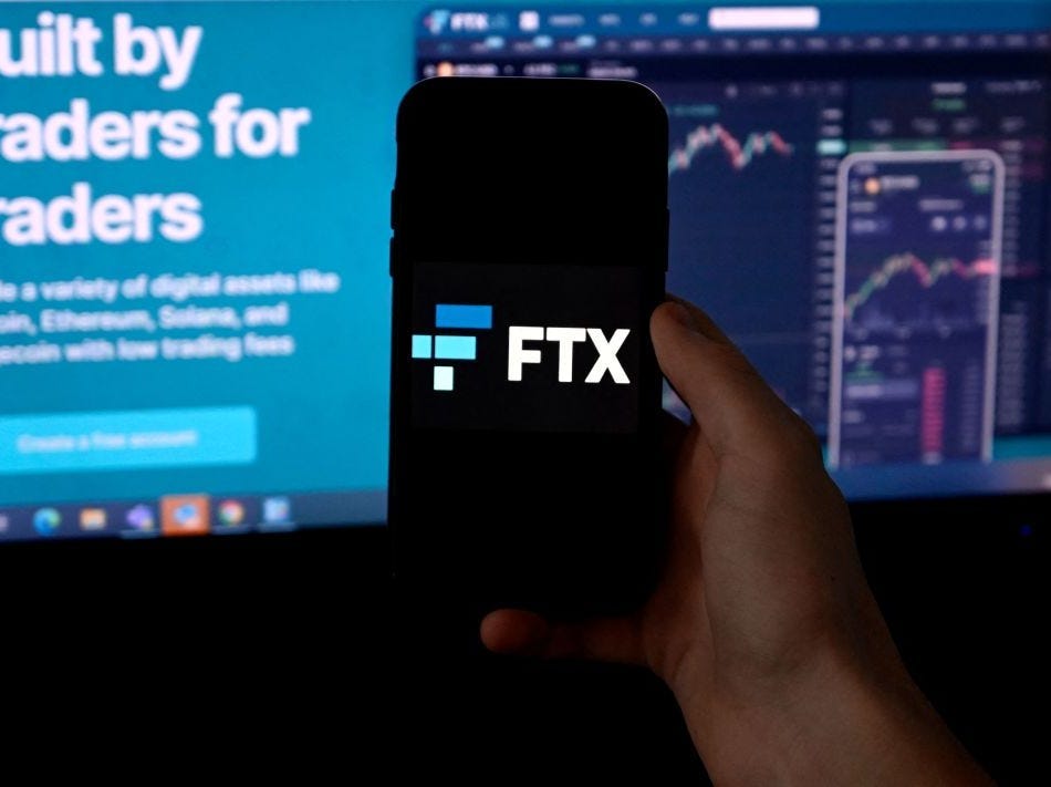 Illustration photo shows a smart phone screen displaying the logo of FTX, the crypto exchange platform, with a screen showing the FTX website