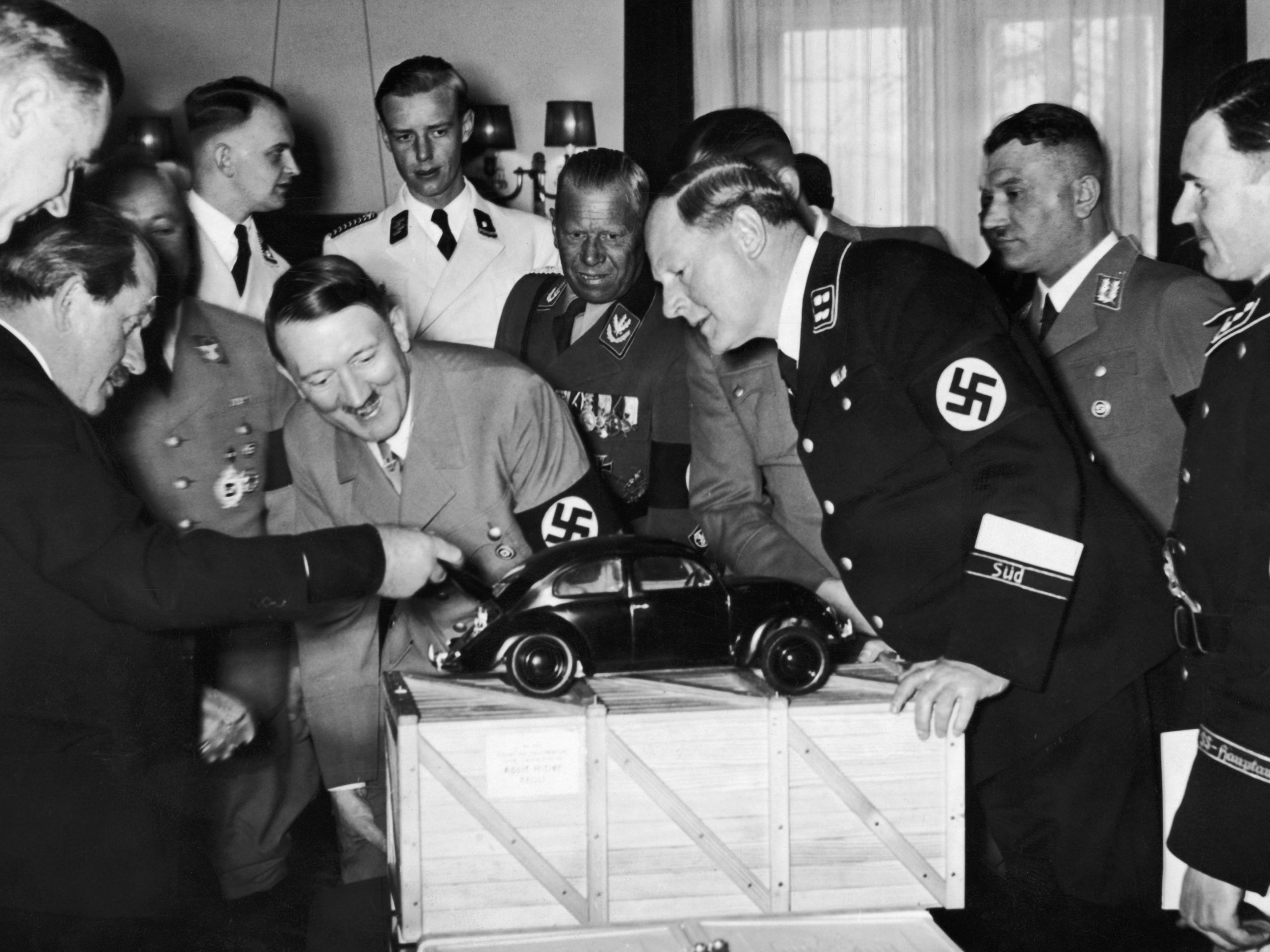Nazi leider Adolf Hitler (1889 - 1945) bewondert een model van de Volkswagen auto en is geamuseerd als hij de motor in de kofferbak aantreft. Hij is met de ontwerper Ferdinand Porsche (links), en rechts staan Korpsfuhrer Huehnlein, Dr Ley, Schmeer en Werlin.