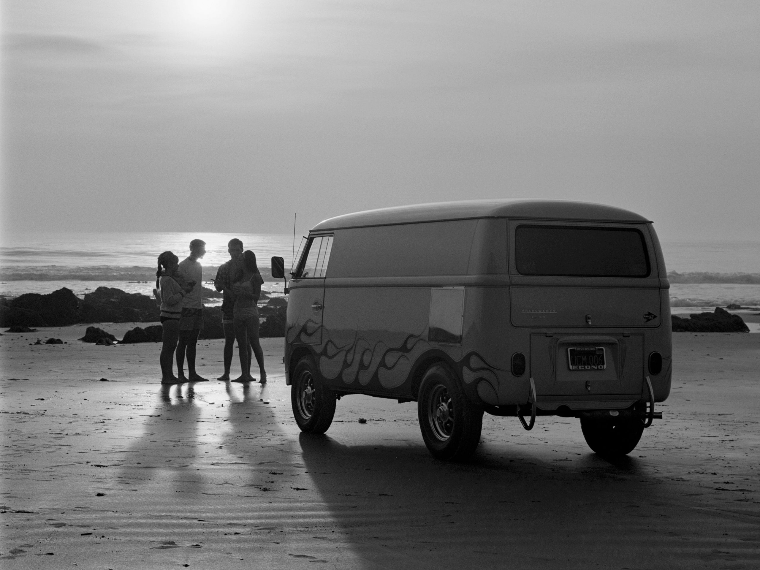 Zonsondergang op een strand in Zuid-Californië met de US Rubber Custom VW Volkswagen Bus en een groep jonge surfers